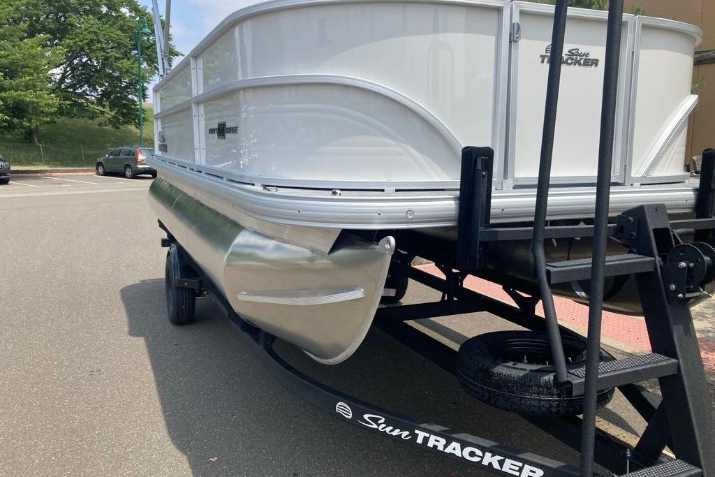 2026 Sun Tracker Party Barge 18 DLX pontoon boat on trailer in parking lot.