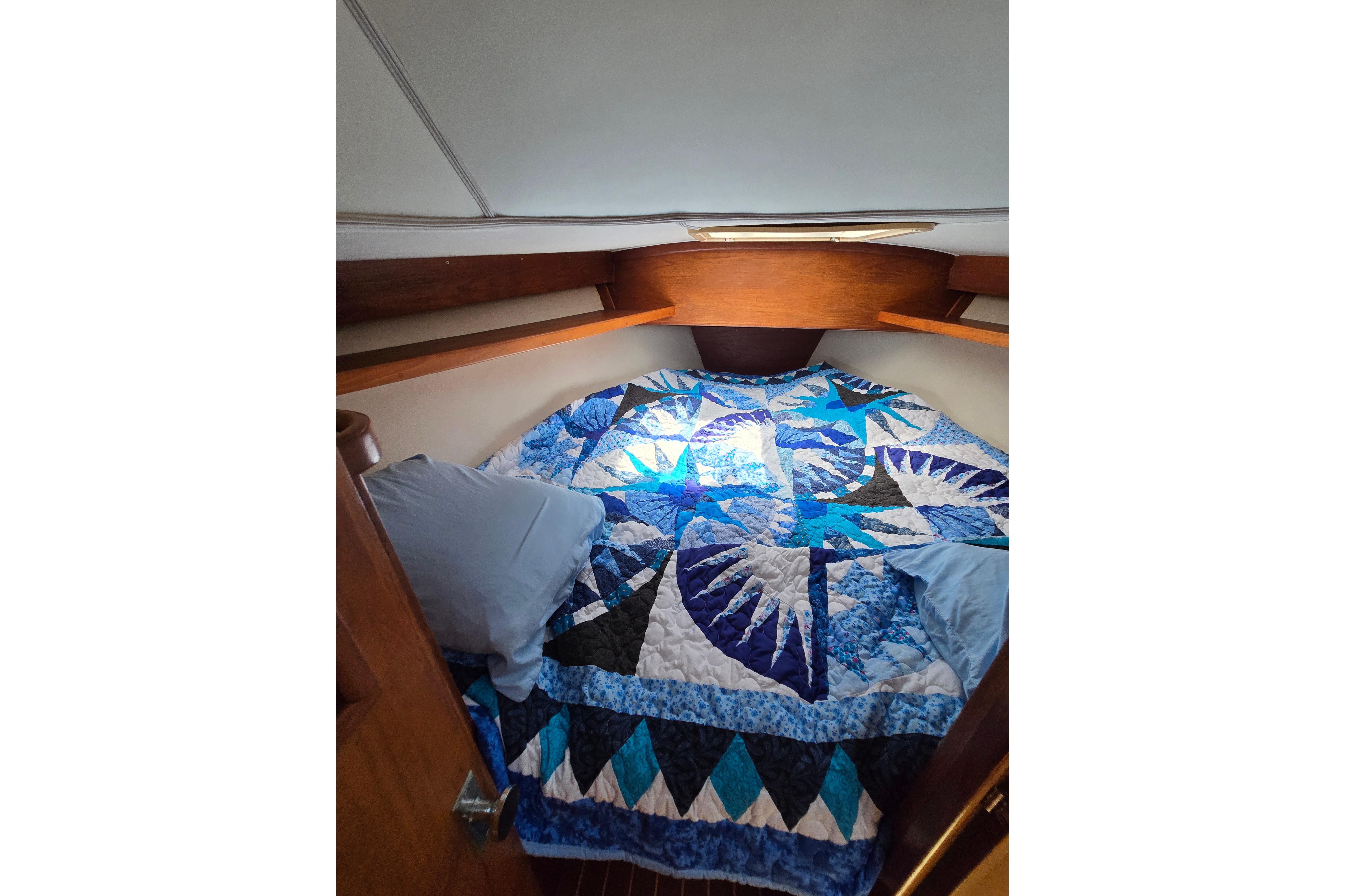 Cozy cabin interior of 1993 Caliber 35 sailboat with colorful quilted bedding.