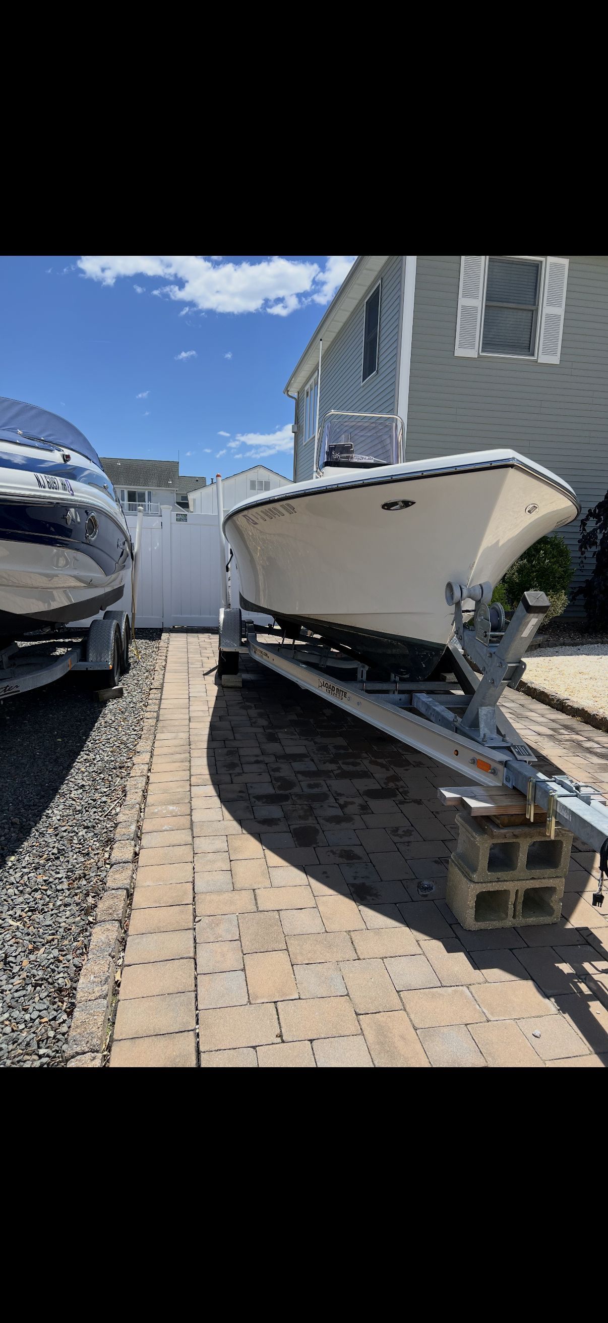A 2020 Center Console Maycraft boat on a trailer next to a house.