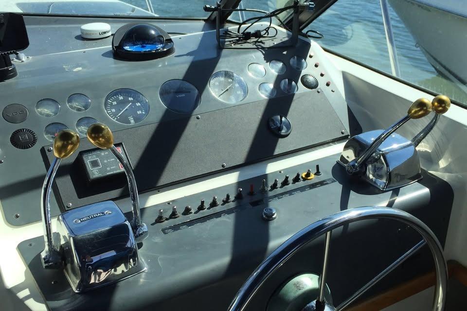Helm of 1989 Tiara Yachts 3100 Open with steering wheel and control levers.
