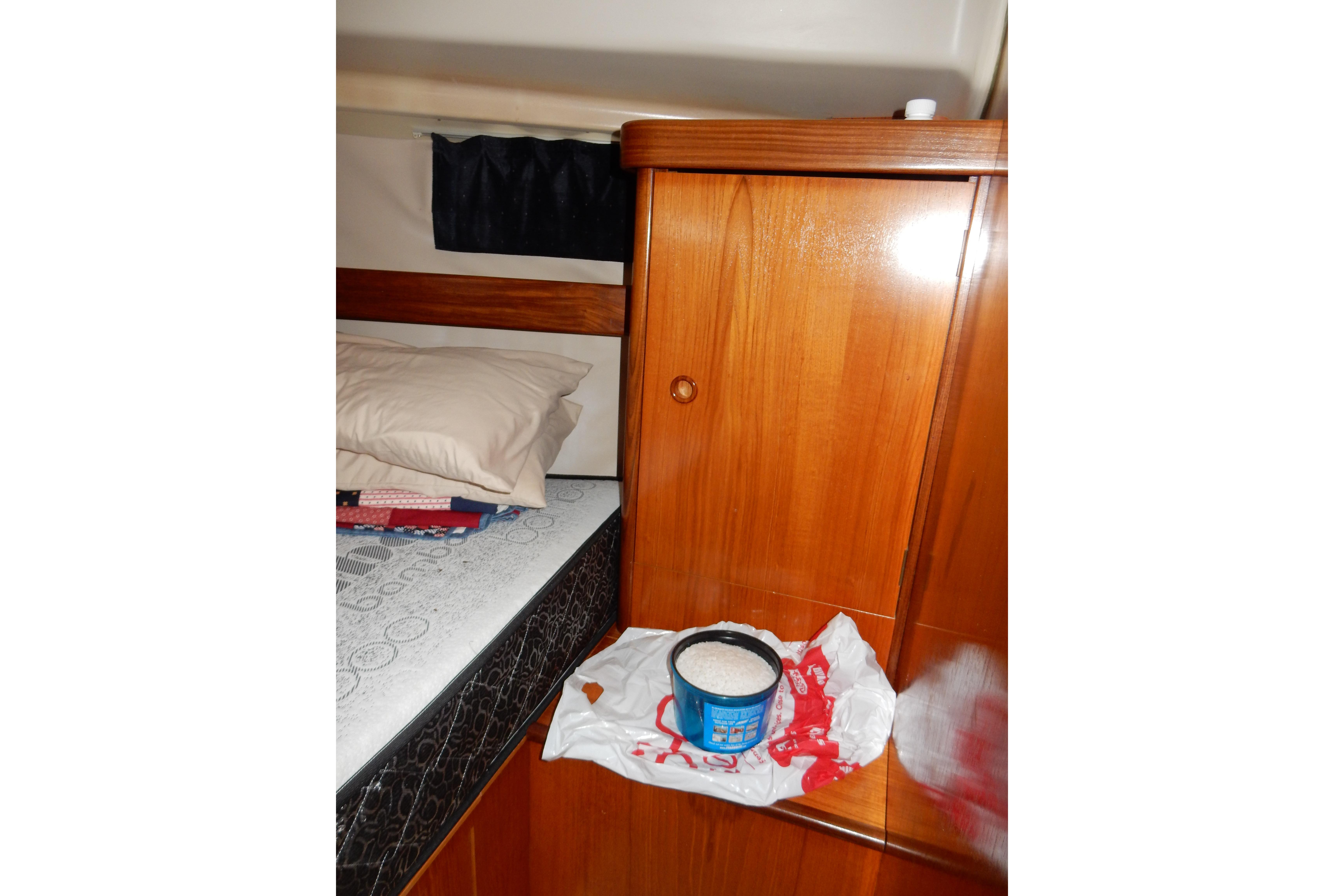 Interior cabin of 1991 Beneteau Oceanis 370 with wooden cabinetry and bedding.