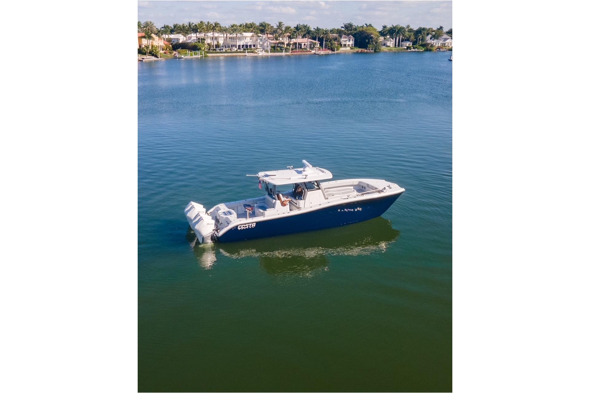 2025 Costa Custom Boats 34 cruising on a serene lake with waterfront homes.