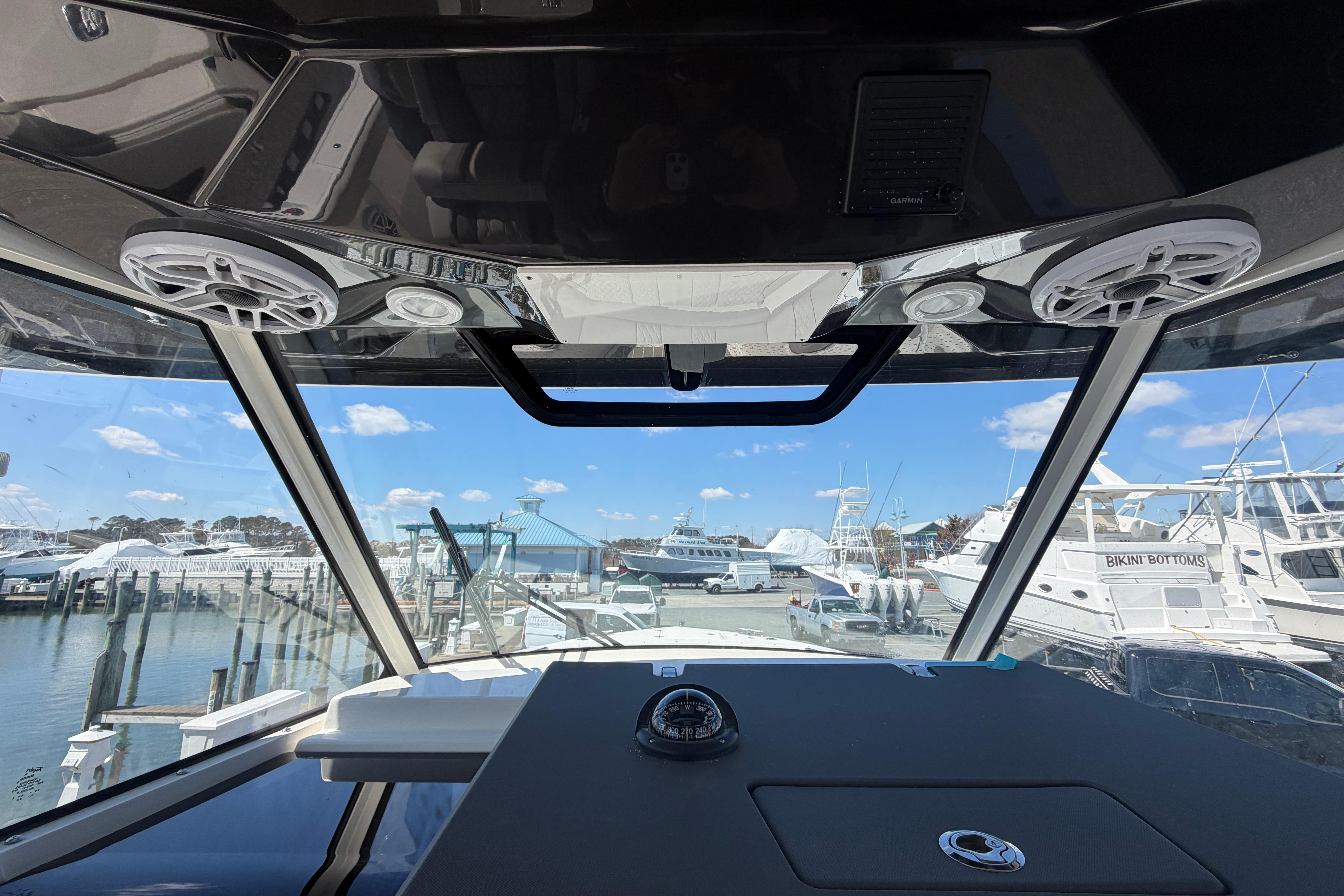 Interior view of 2026 Pursuit S 358 Sport boat at marina, showcasing dashboard and speakers.