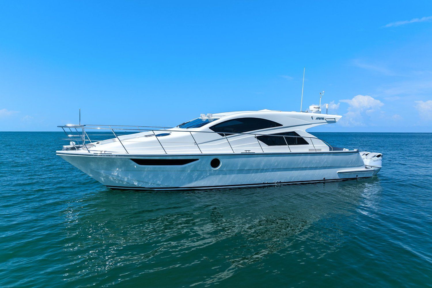 A sleek, white catamaran on calm water under a clear sky.