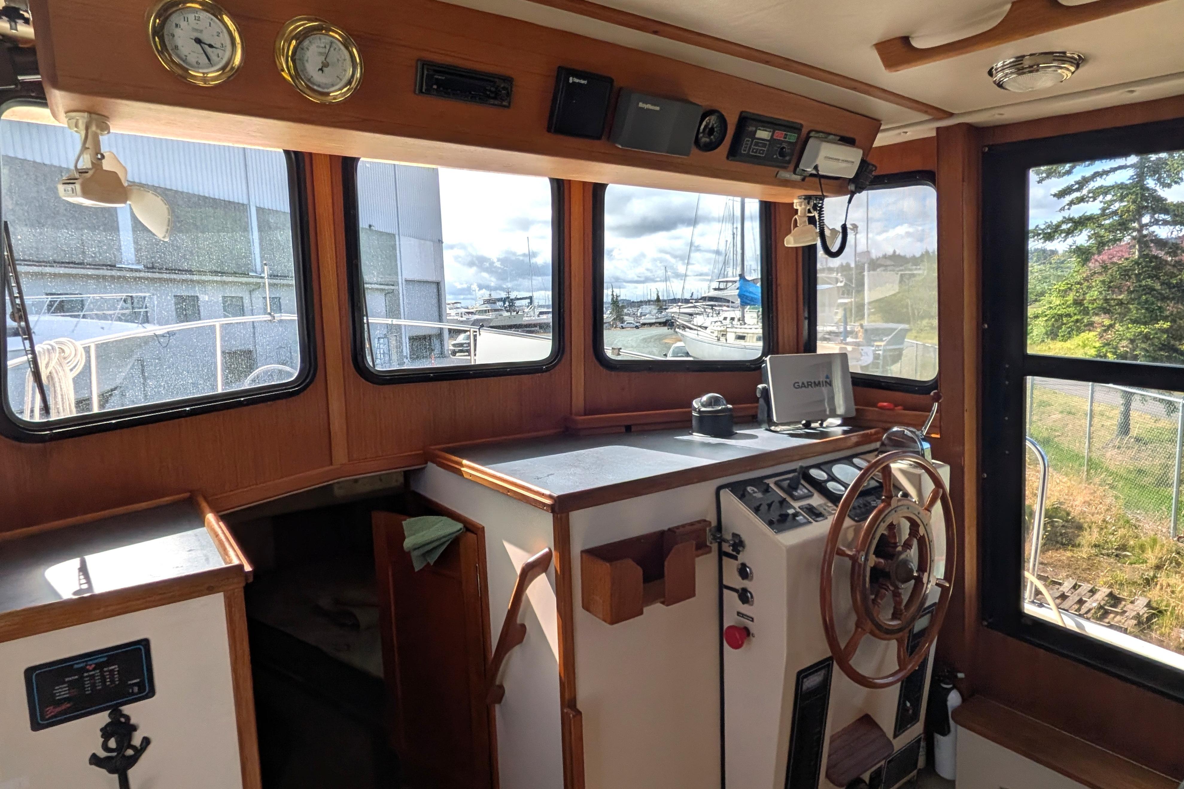 Interior of a 1998 Nordic Tug 32 boat with navigation equipment and wooden steering wheel.