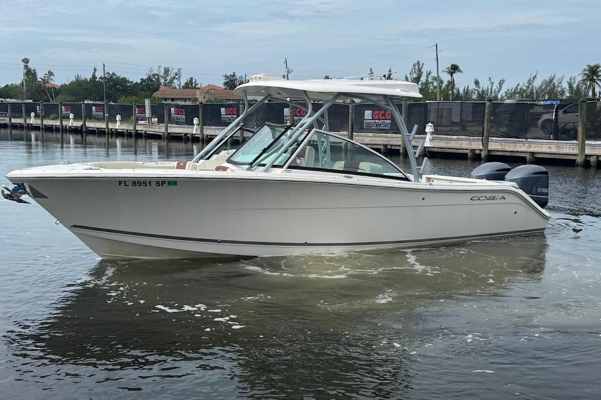 2020 Cobia 280 Dual Console boat on calm water near a dock.