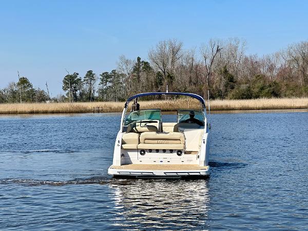 A 2018 Regal 3300 boat cruising on calm water with trees in the background.