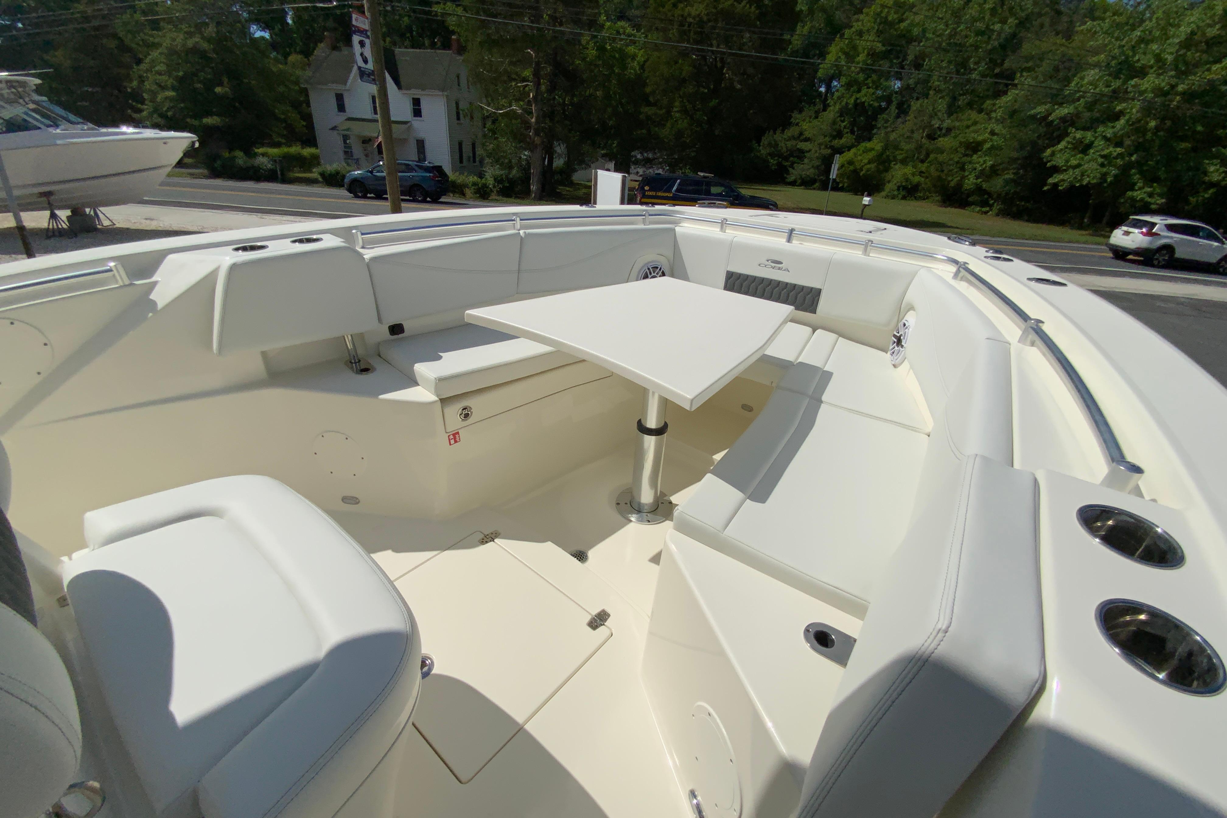 2027 Cobia 320 Center Console boat interior with seating and table, parked outdoors.