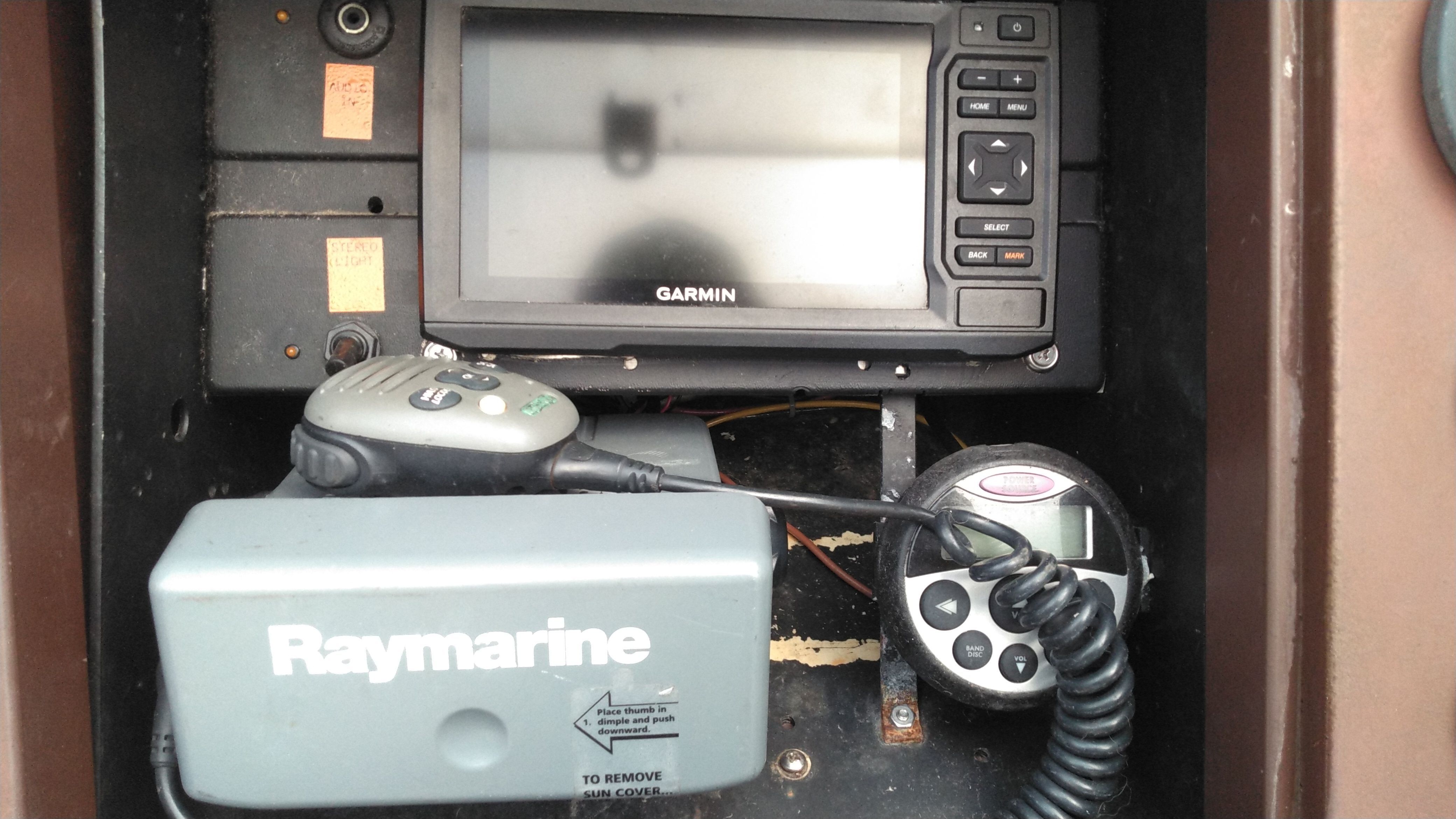 A boat cockpit with Garmin navigation system and Raymarine equipment.