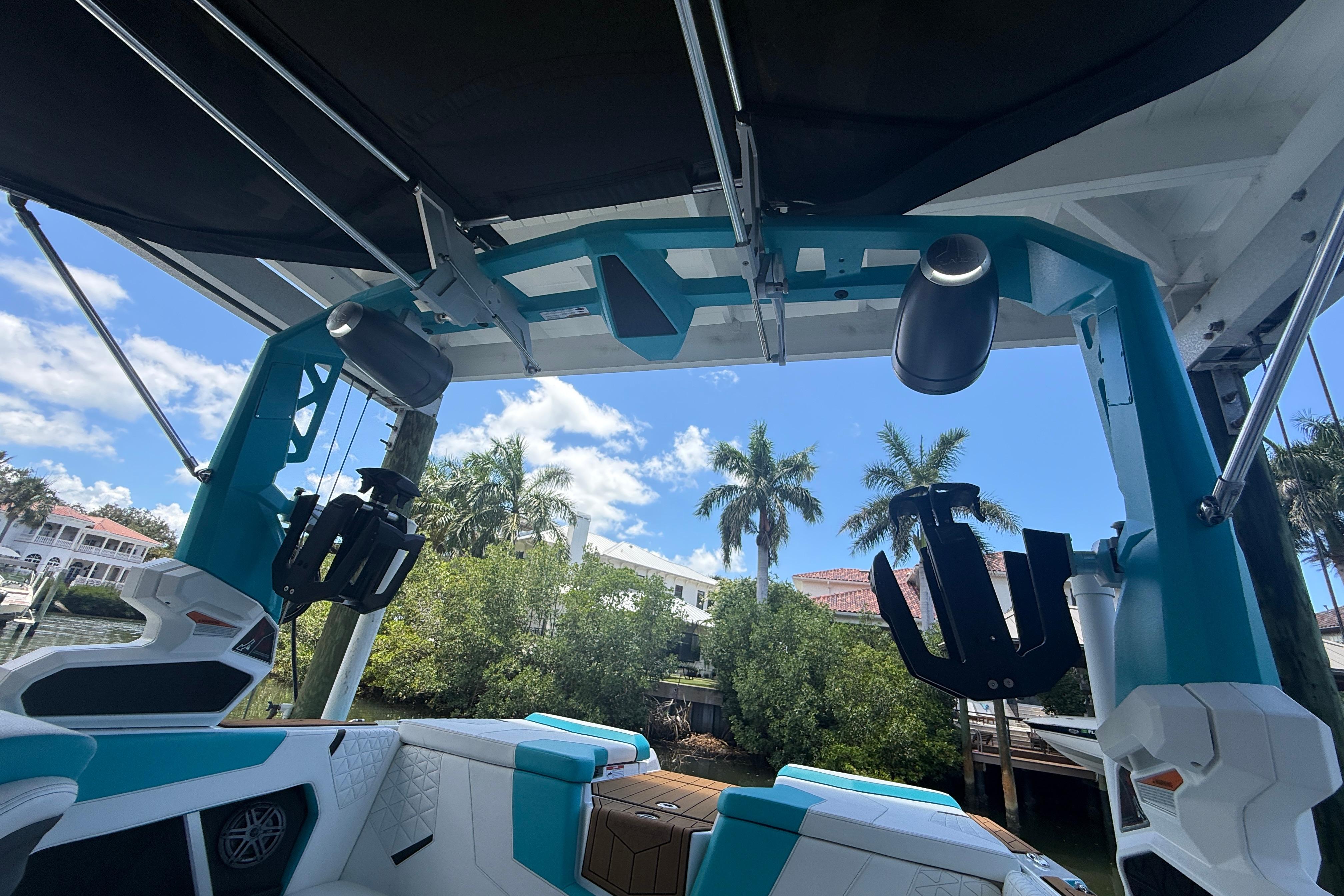 2024 Nautique Super Air Nautique GS20 interior with speakers and wakeboard racks, under sunny sky.