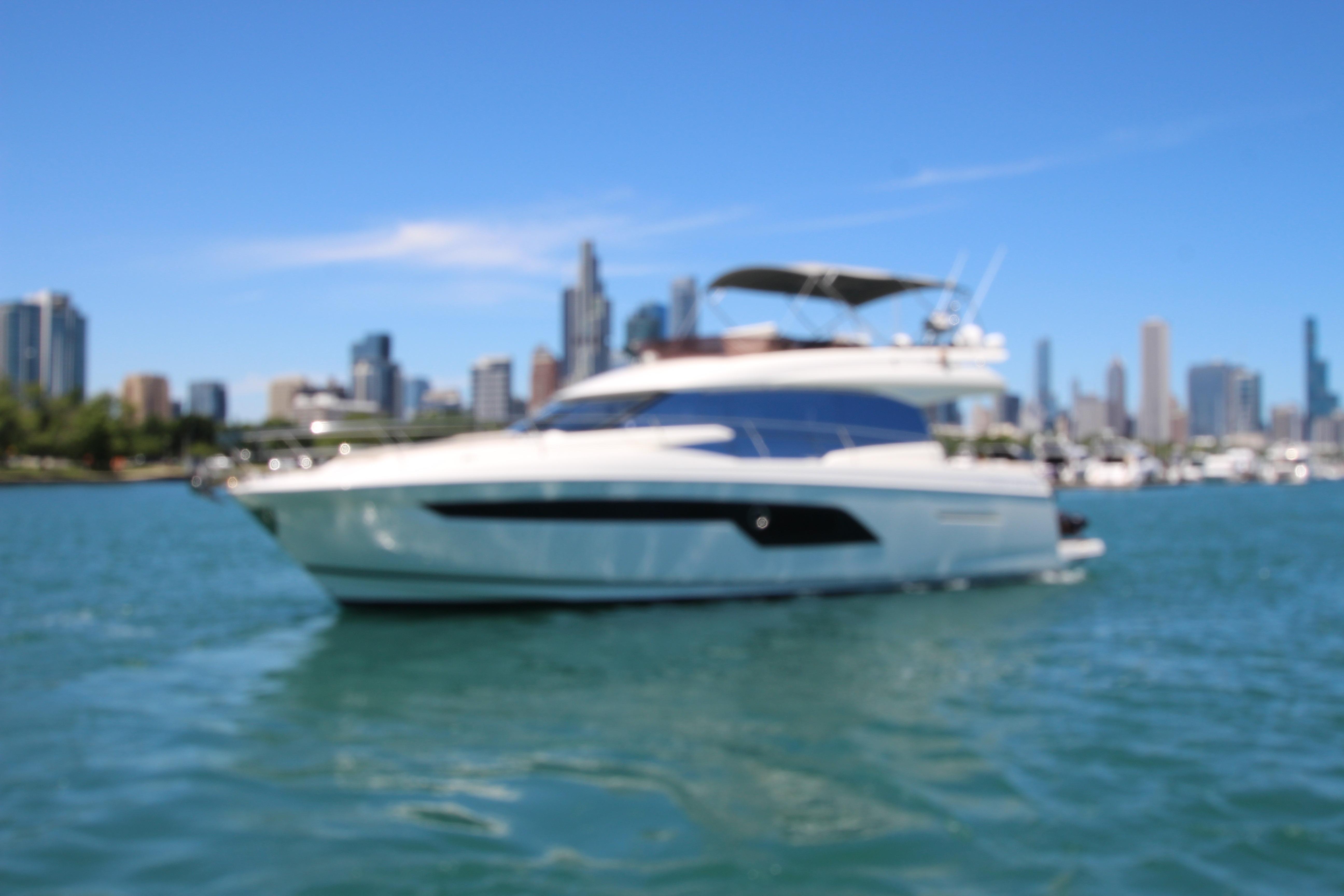 Luxury 2022 Prestige 520 yacht cruising near city skyline on a sunny day.