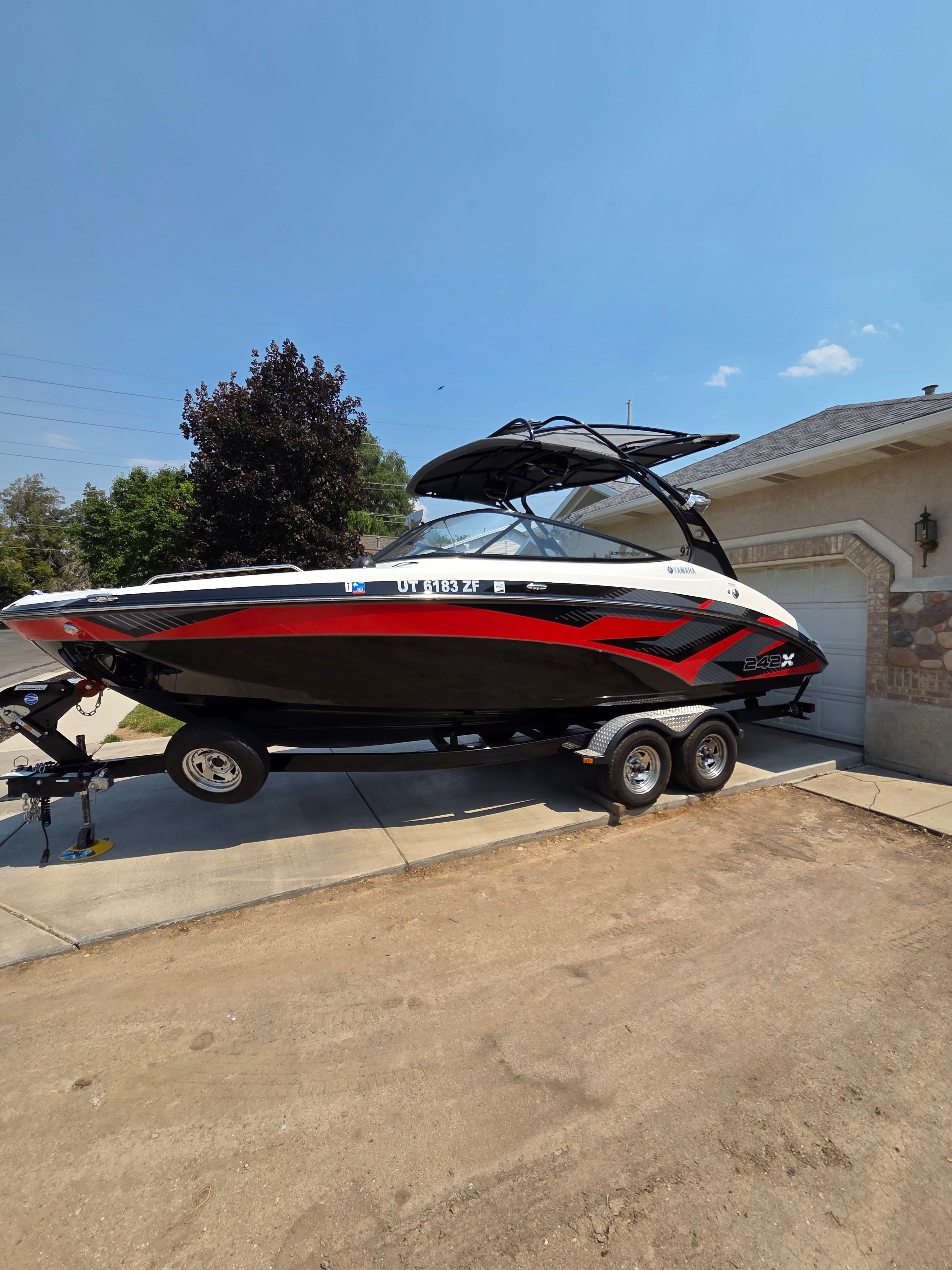 A 2016 Yamaha 242X E-Series boat on a trailer in a driveway.