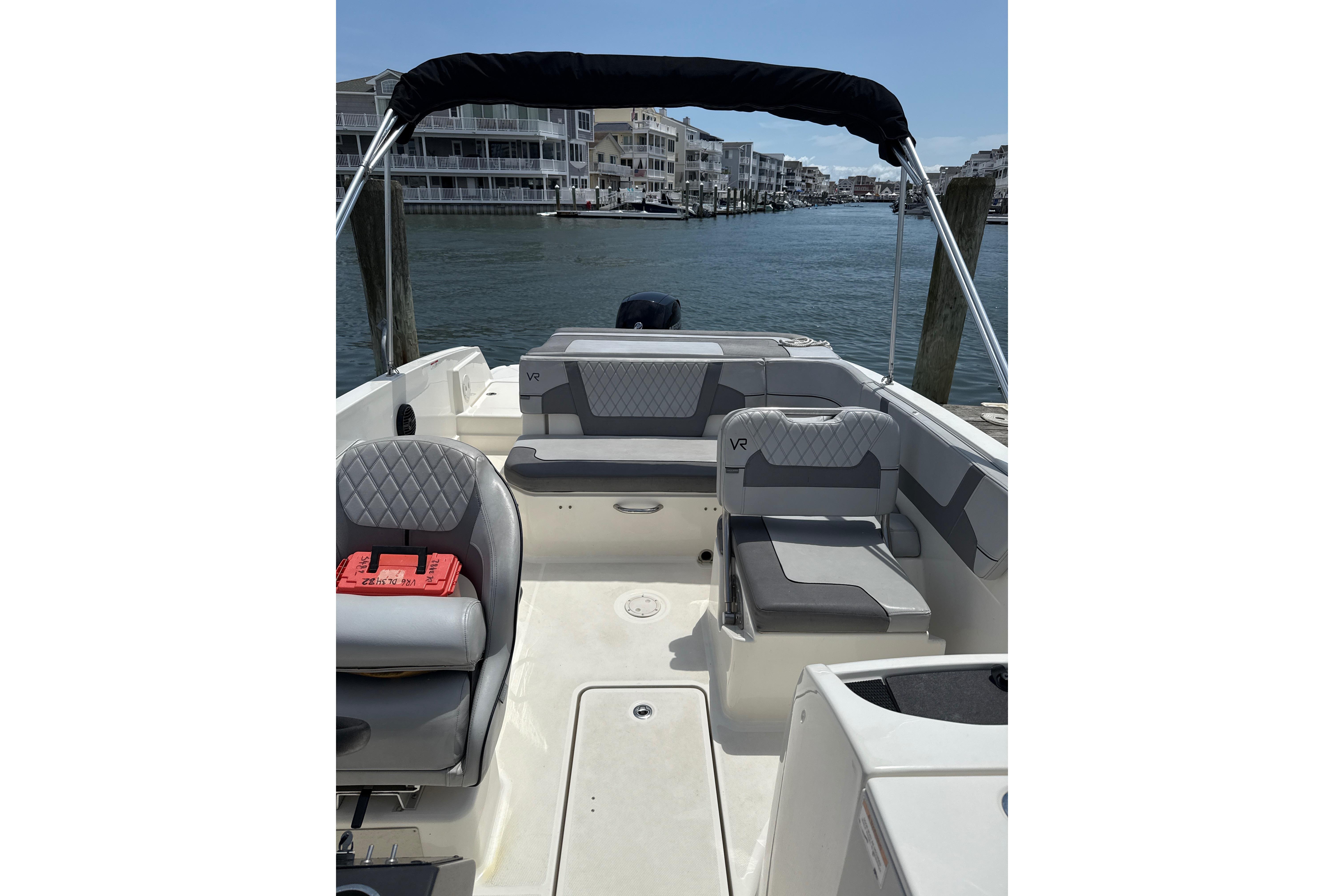 2023 Bayliner VR6 Bowrider OB interior with seating, docked by waterfront homes.