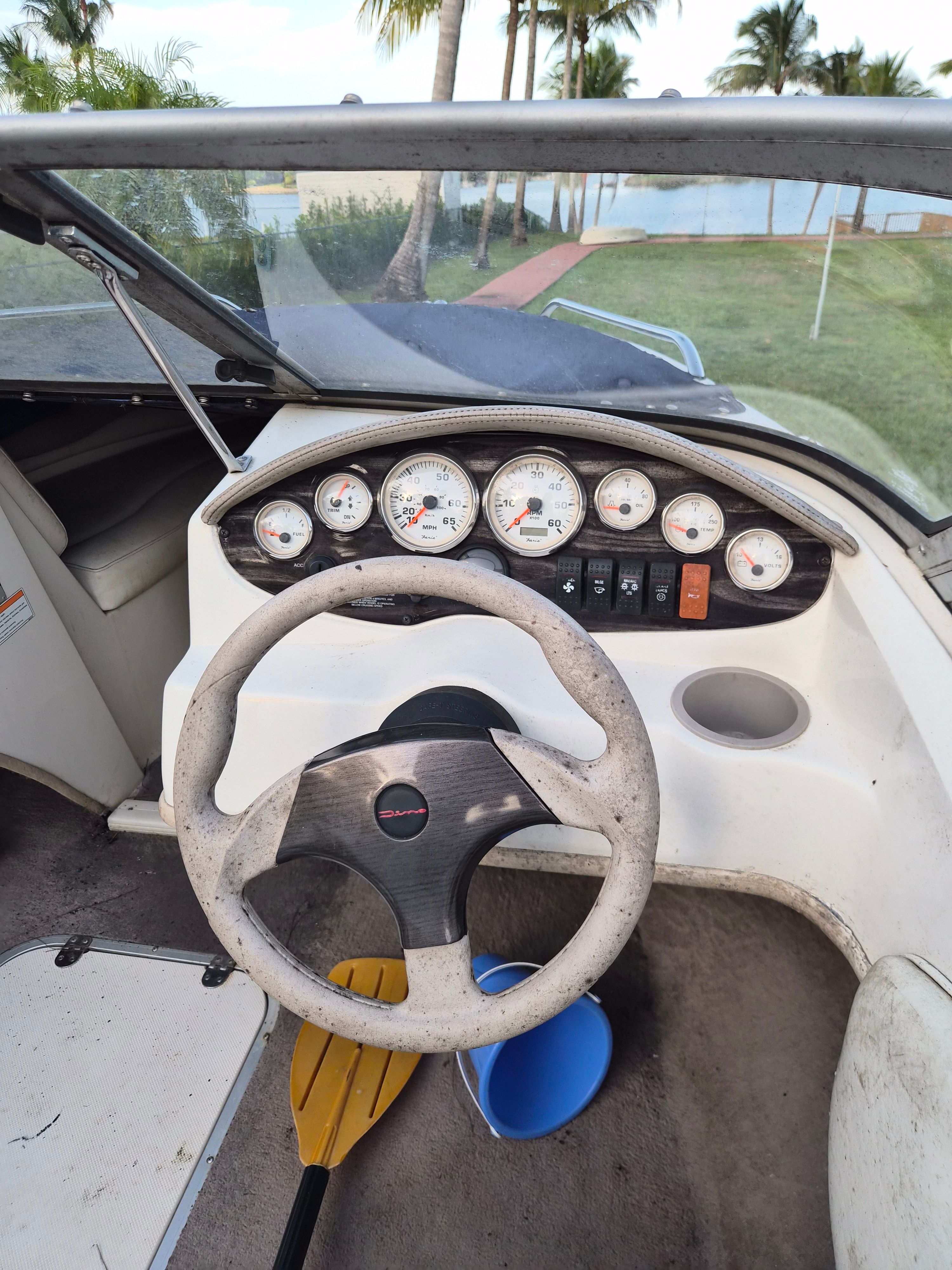 The image shows a boat cockpit with a steering wheel and multiple instrument gauges.