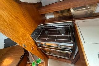 1986 Beneteau First 305 yacht kitchen with stove and wooden cabinetry.