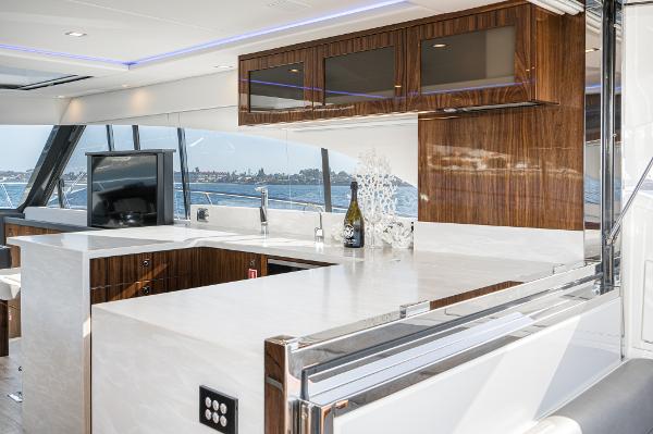 Luxurious interior of 2021 Riviera 5400 Sport Yacht with modern kitchen and scenic views.