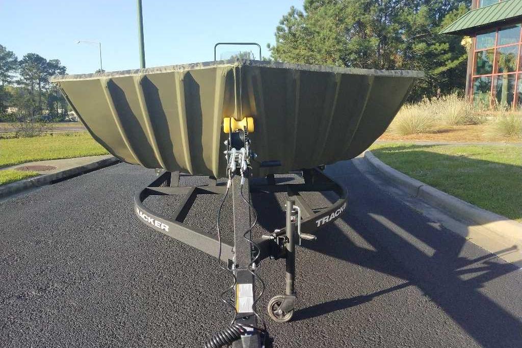 2026 Tracker Grizzly 2072 CC boat on trailer, parked on asphalt near greenery.