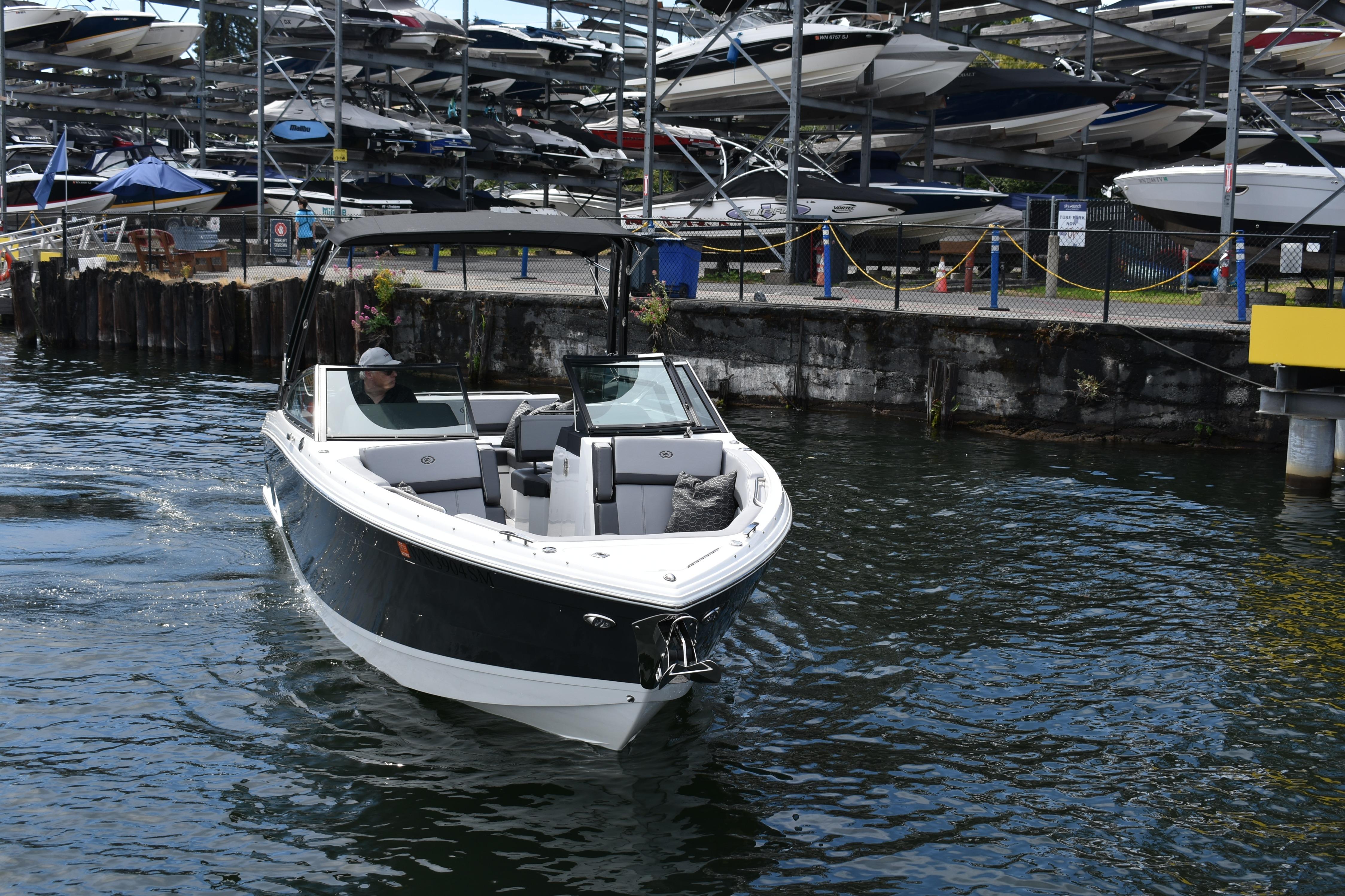 2023 Cobalt R8 boat navigating marina waters with docked boats in background.