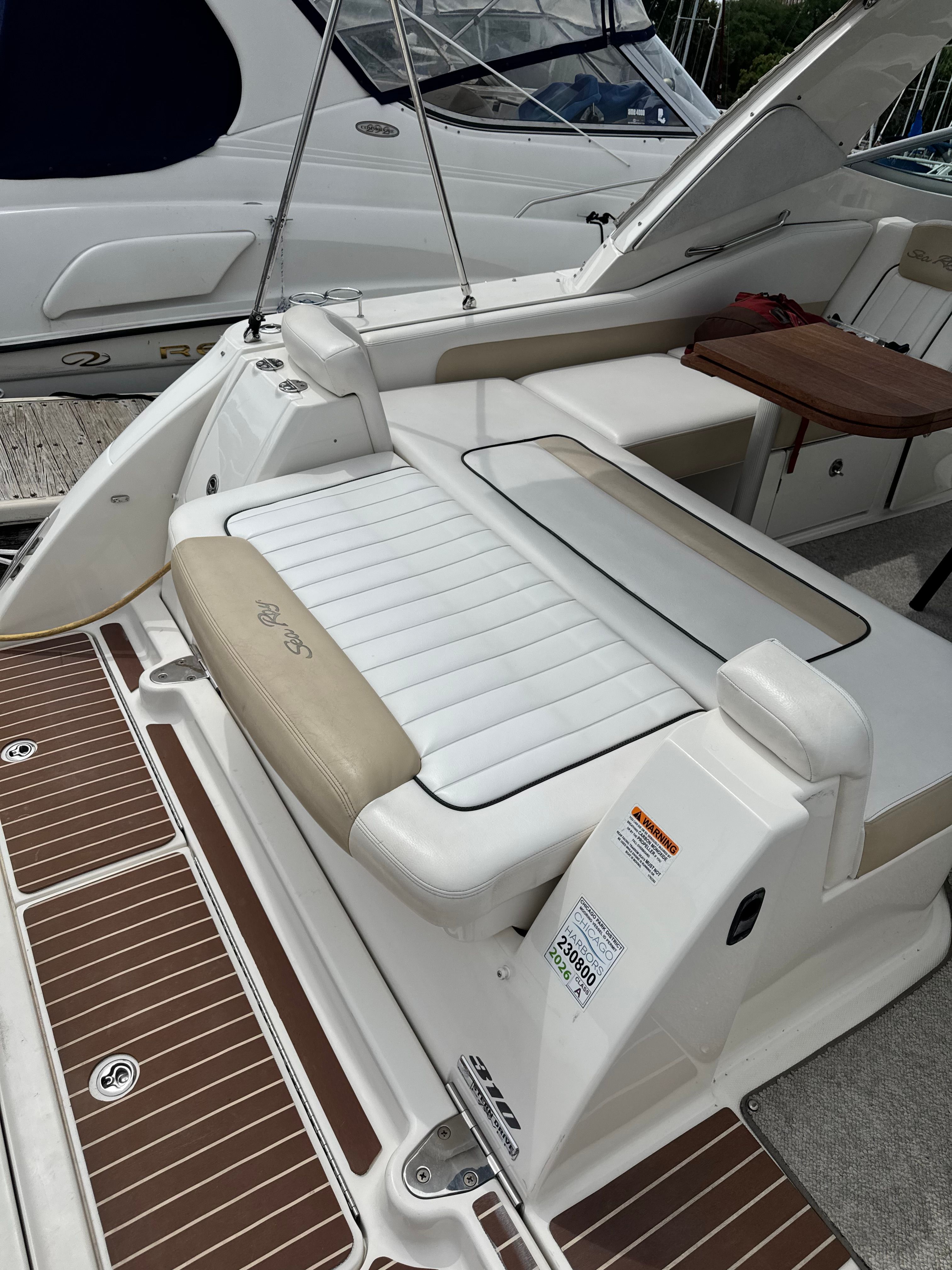 The image shows the stern of a Sea Ray Sundancer 310 with beige and white upholstery.