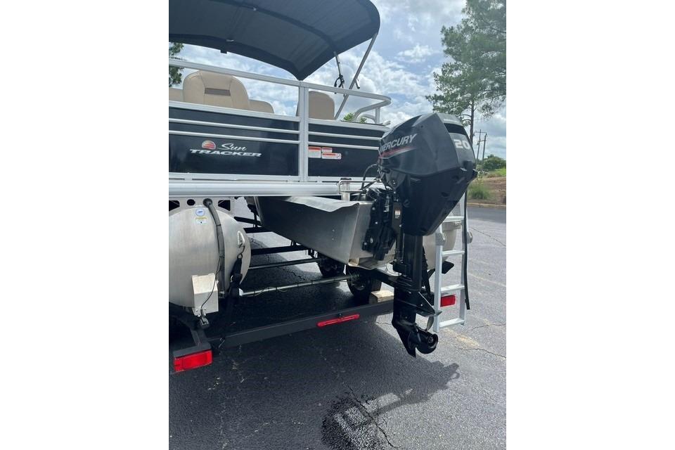 2023 SUNTRACKER Fishing Barge 20 with Mercury outboard motor, parked on asphalt.