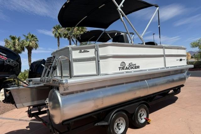 2026 Sun Tracker Party Barge 20 DLX pontoon boat on trailer, under sunny skies.
