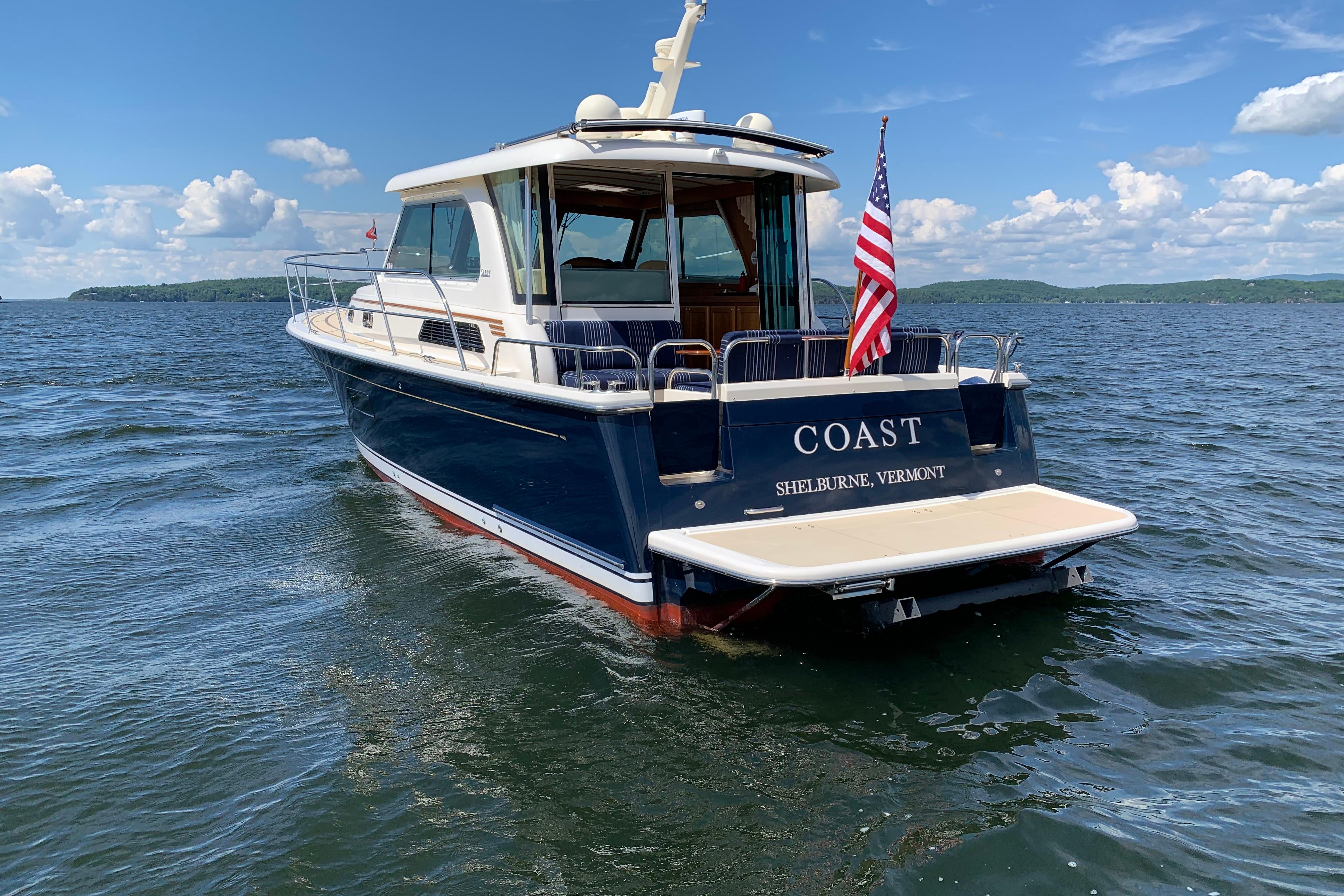 2015 Sabre 38 Salon Express boat on water, American flag, clear sky.