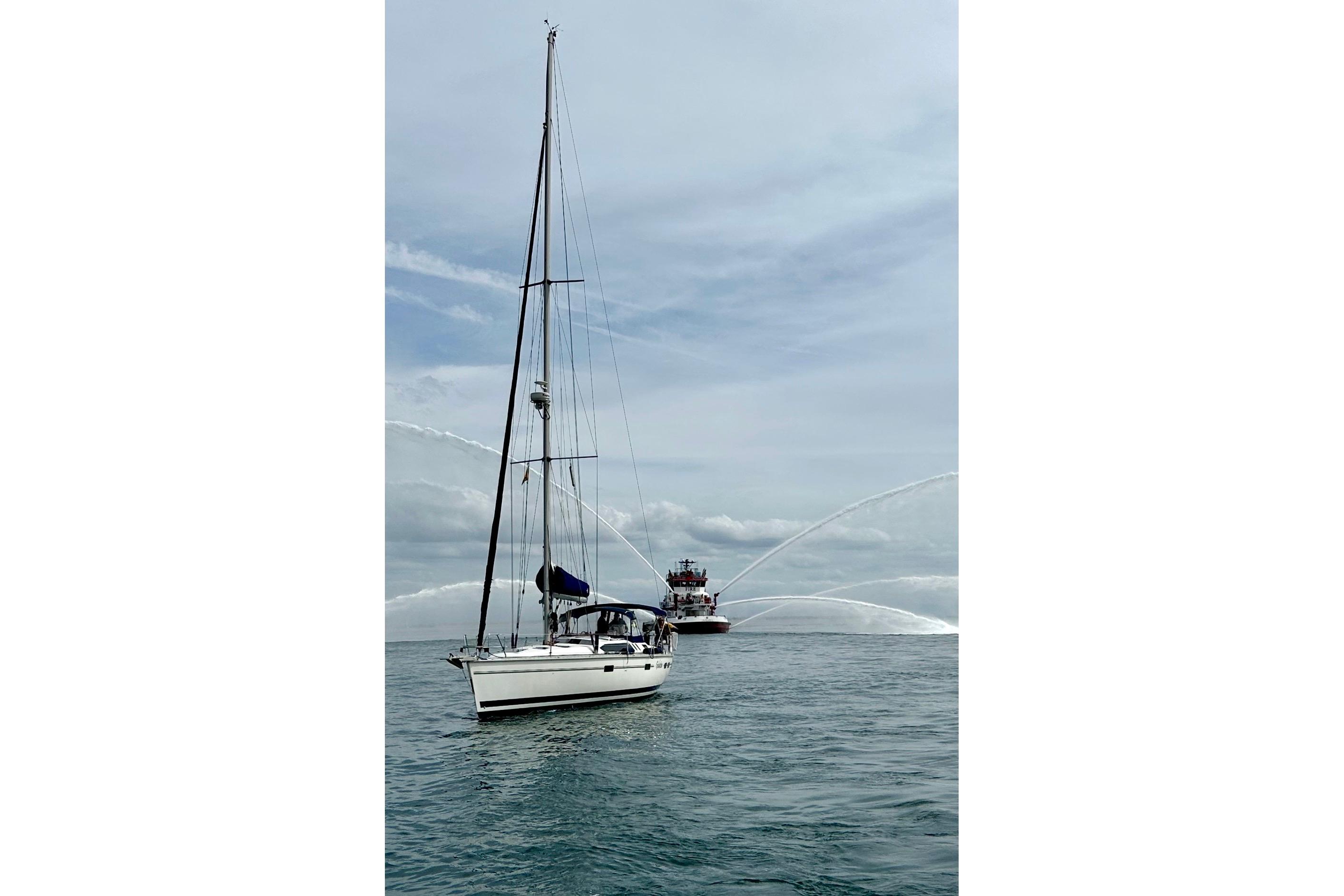 Sailboat Hunter Legend 40.5 (1997) on water with fireboat spraying water in background.