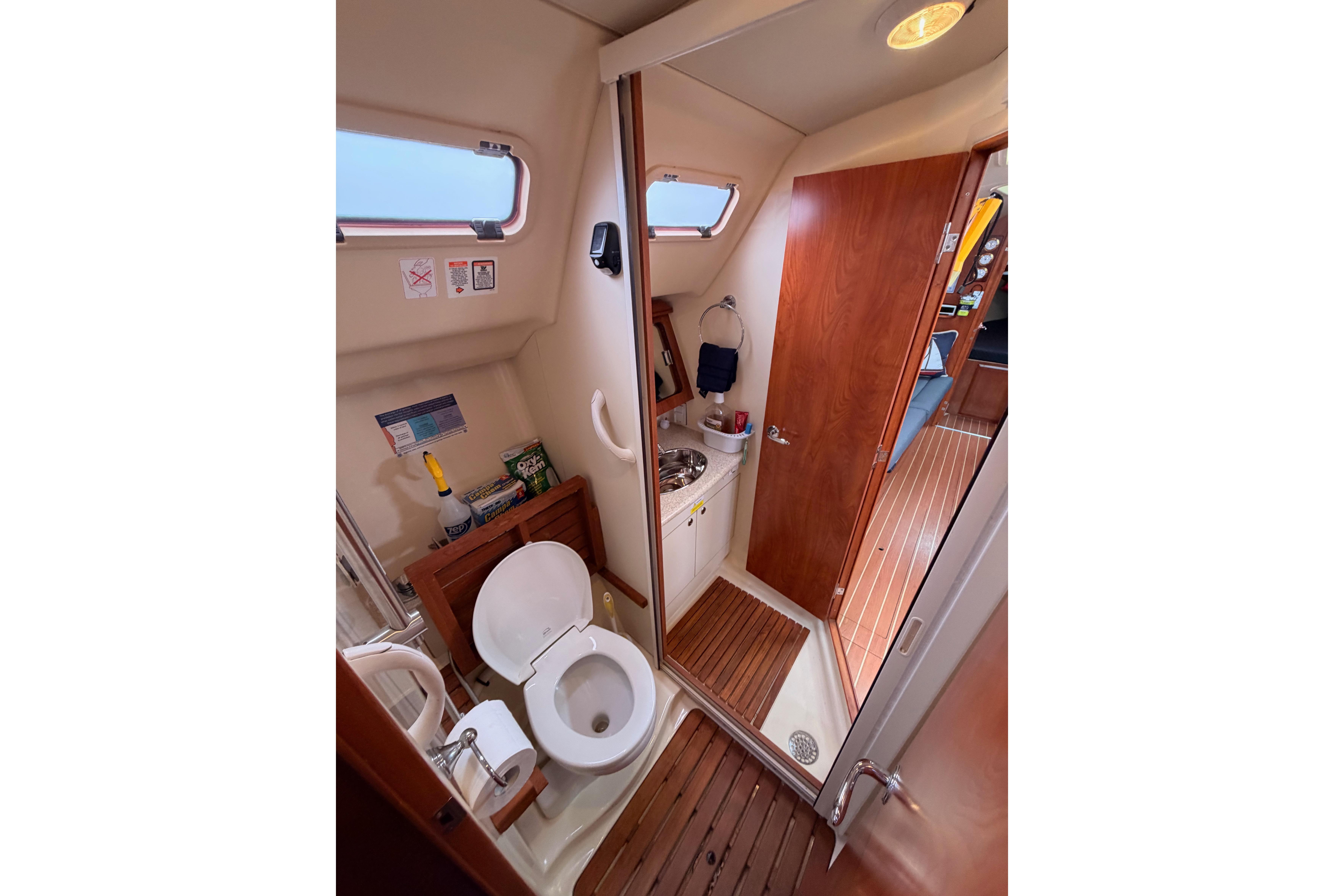Interior of 2009 Hunter 38 sailboat bathroom with toilet, sink, and wooden accents.