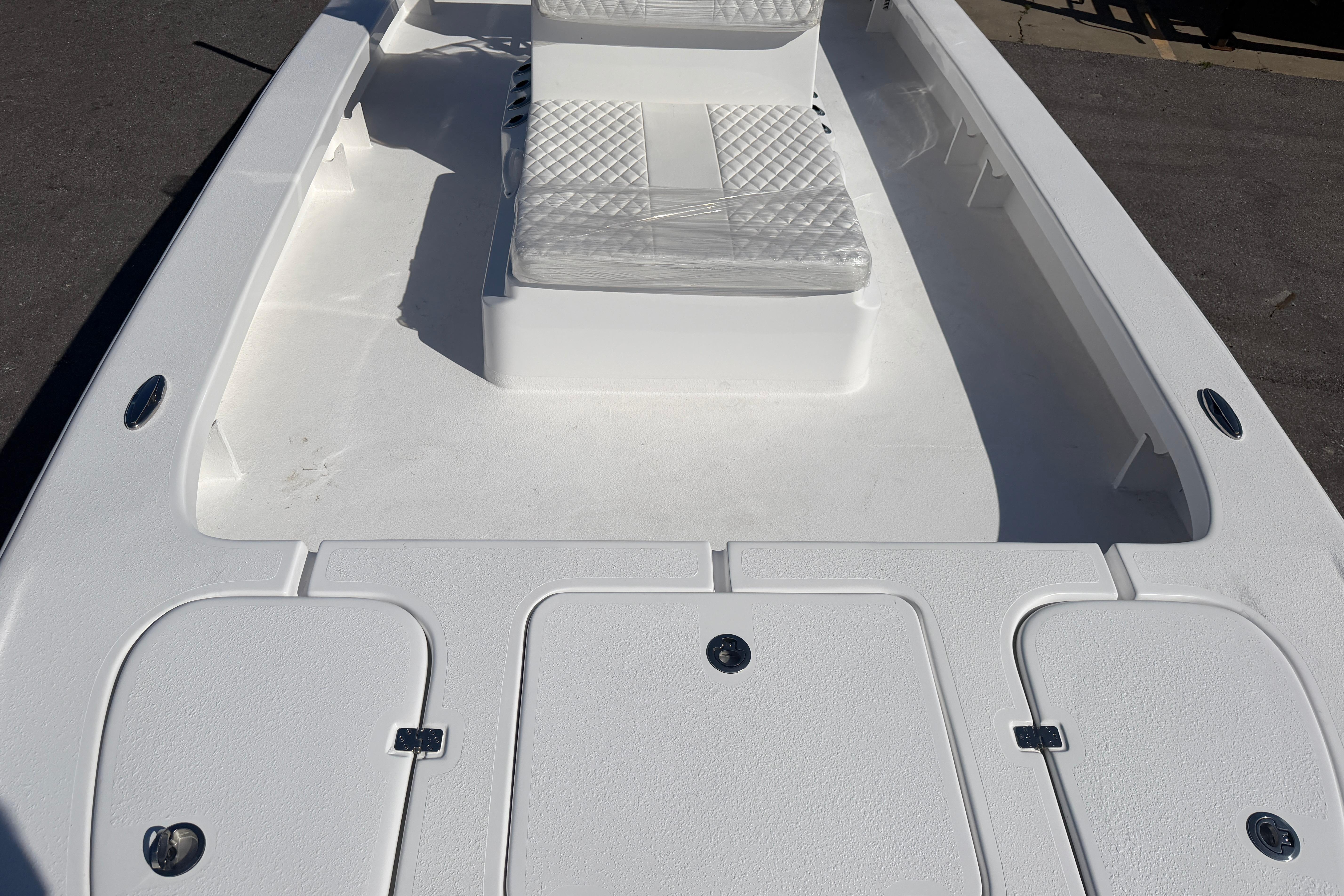 2026 Skuta 24 Cat boat interior with white seating and storage compartments.