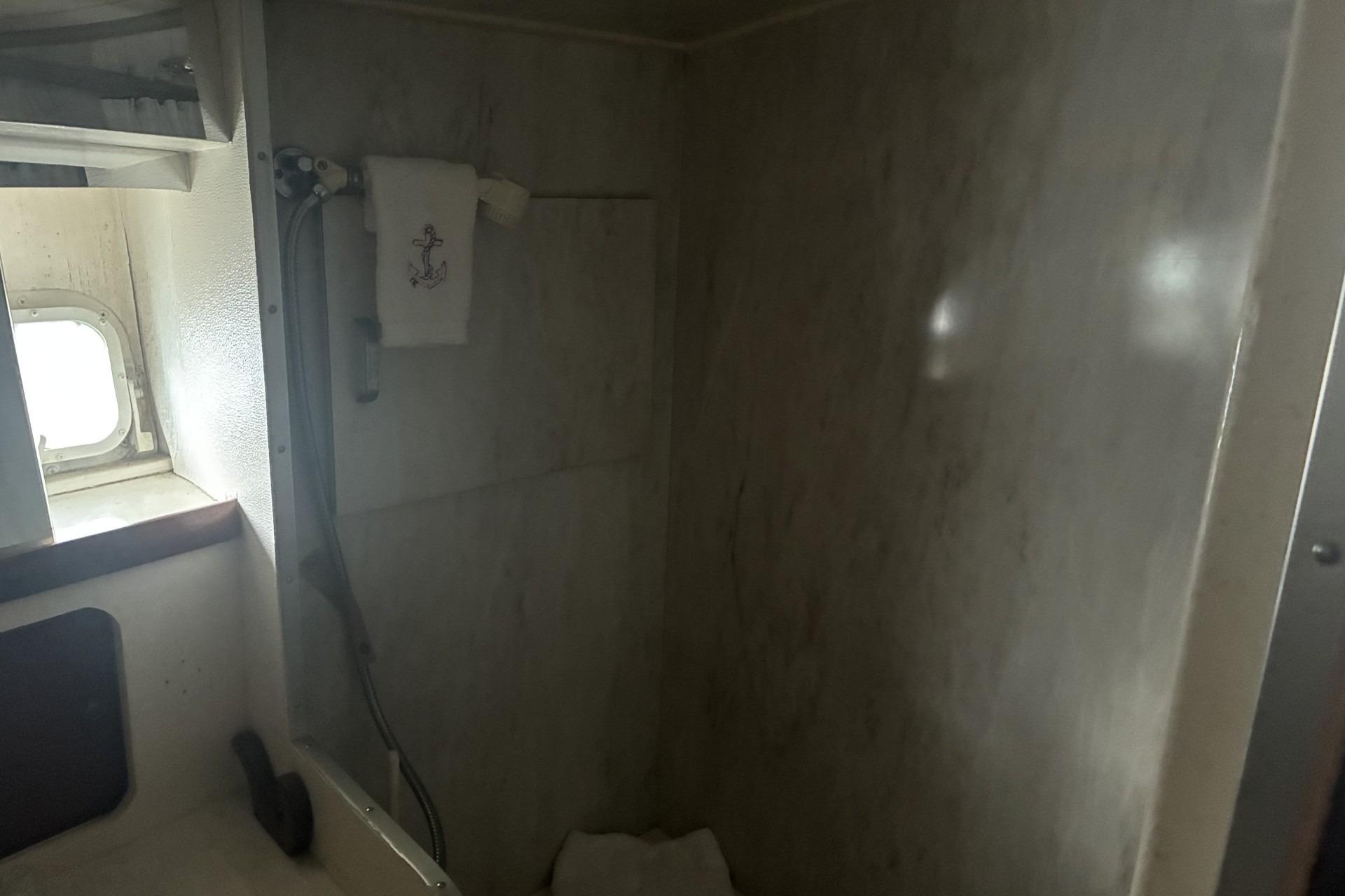 Bathroom interior of 1980 Chris-Craft 360 Commander yacht with shower and porthole.
