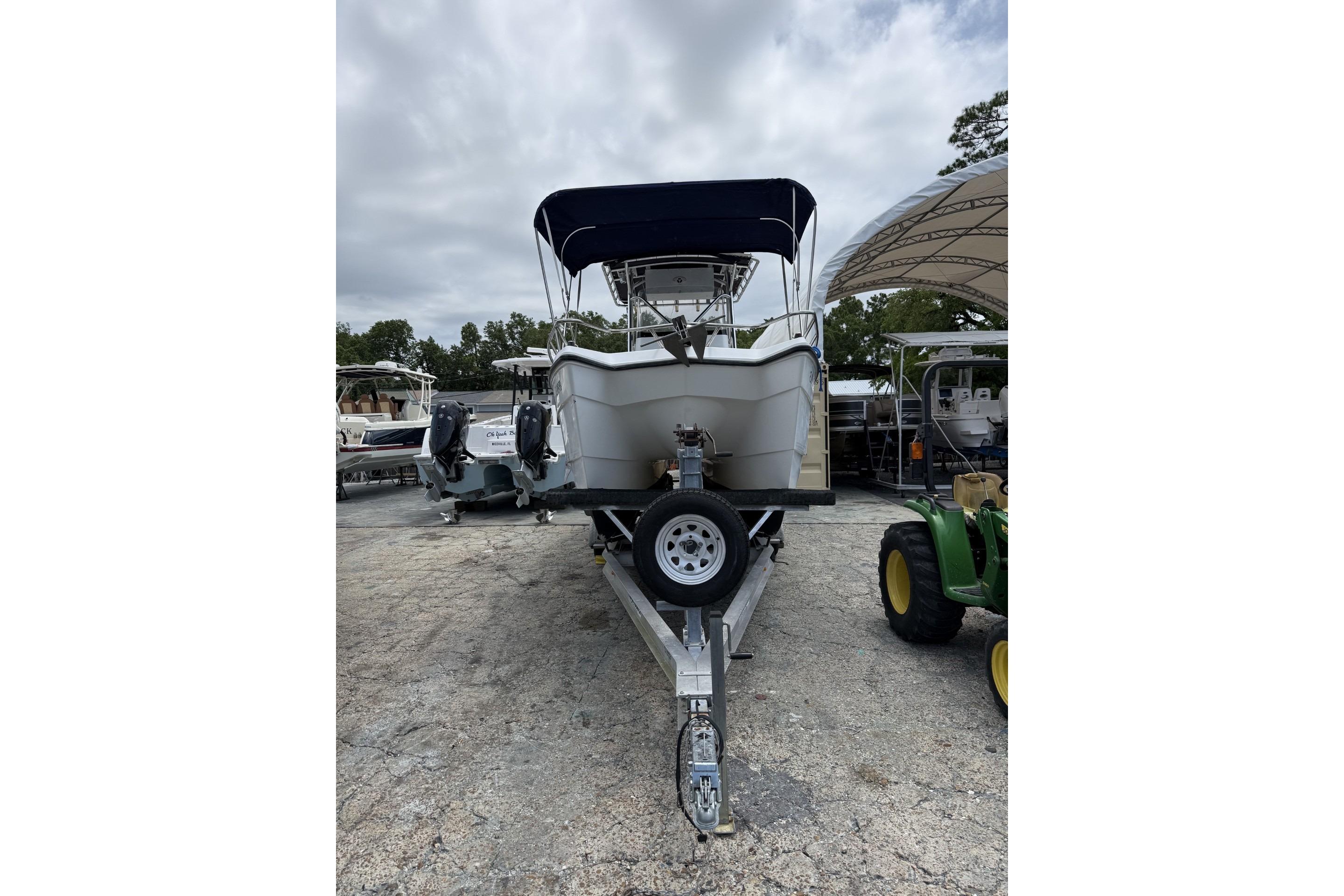 2002 Pro Sports 2200 CC ProKat boat on trailer, parked outdoors under cloudy sky.