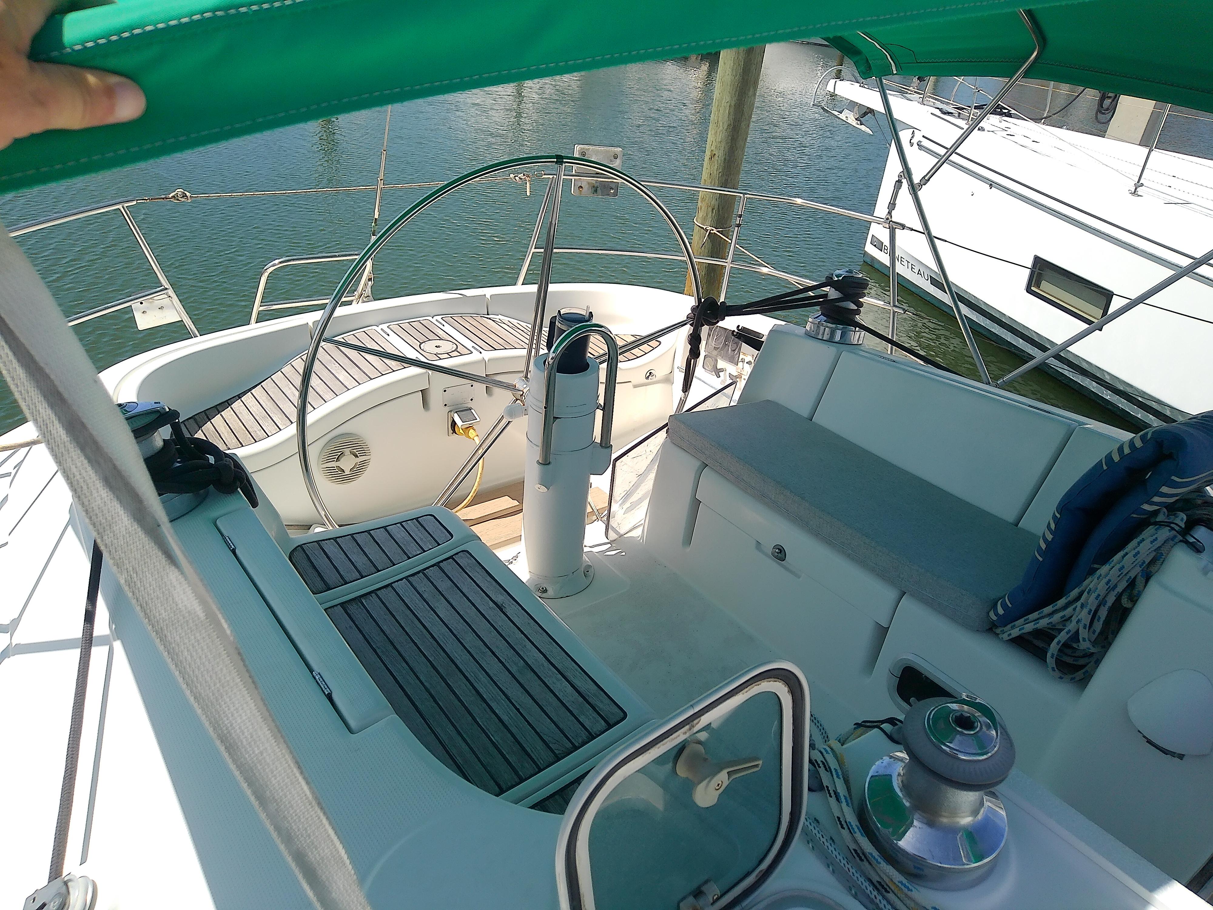 Cockpit of 1995 Beneteau First 42s7 sailboat with green canopy and wooden deck.