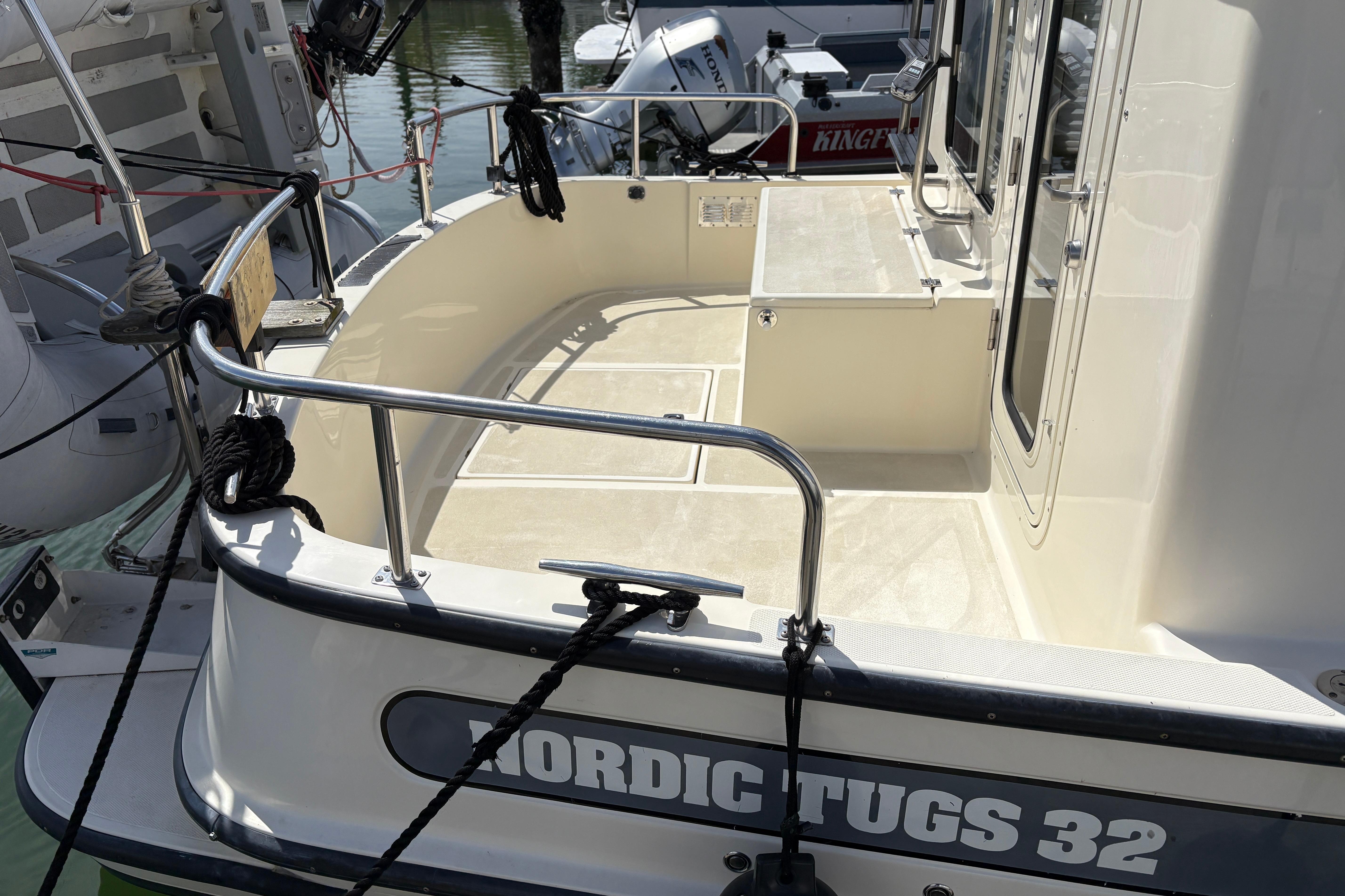2004 Nordic Tug 32 boat deck with railing and mooring ropes in marina.