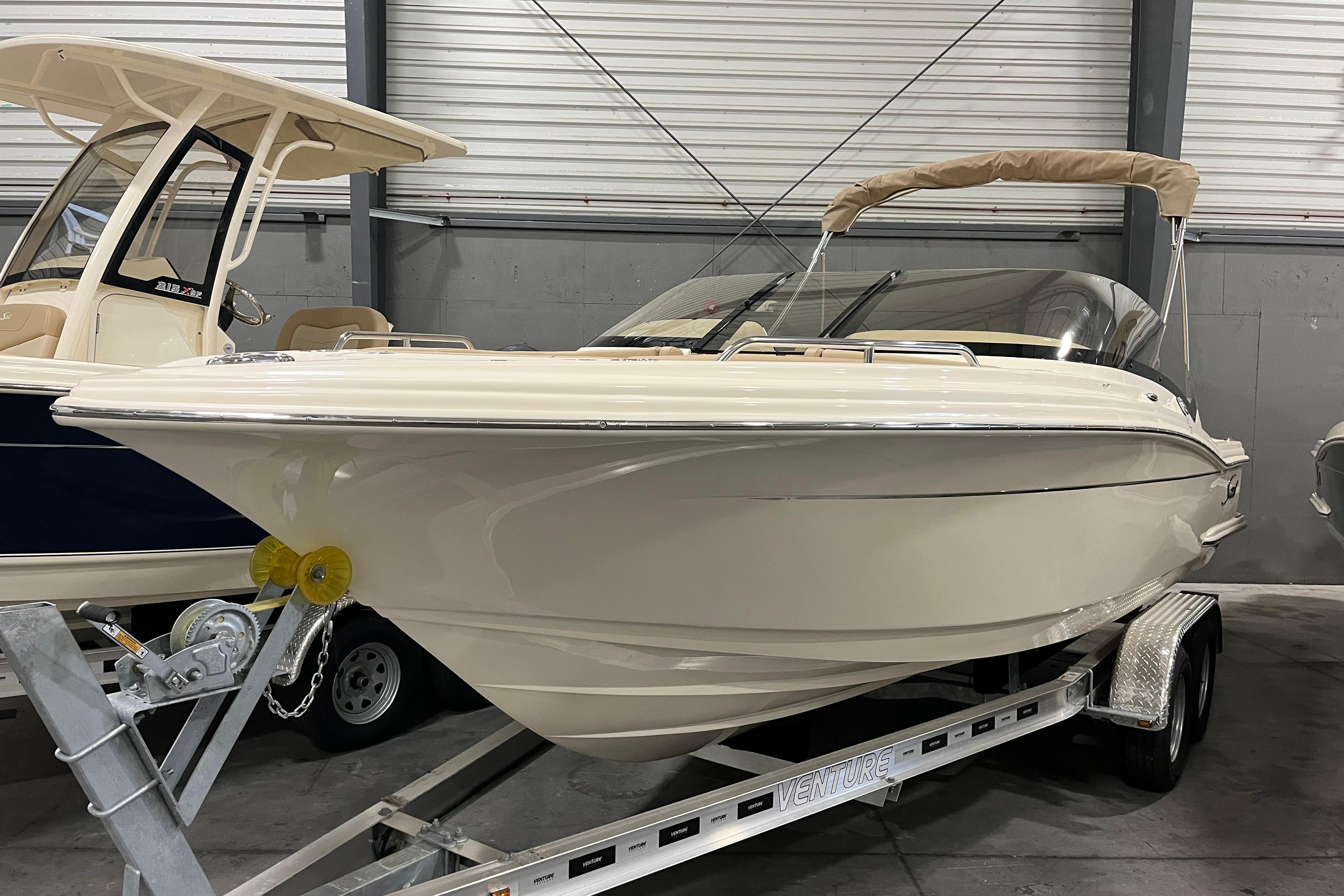 2025 Scout 215 Dorado boat on trailer in indoor storage facility.
