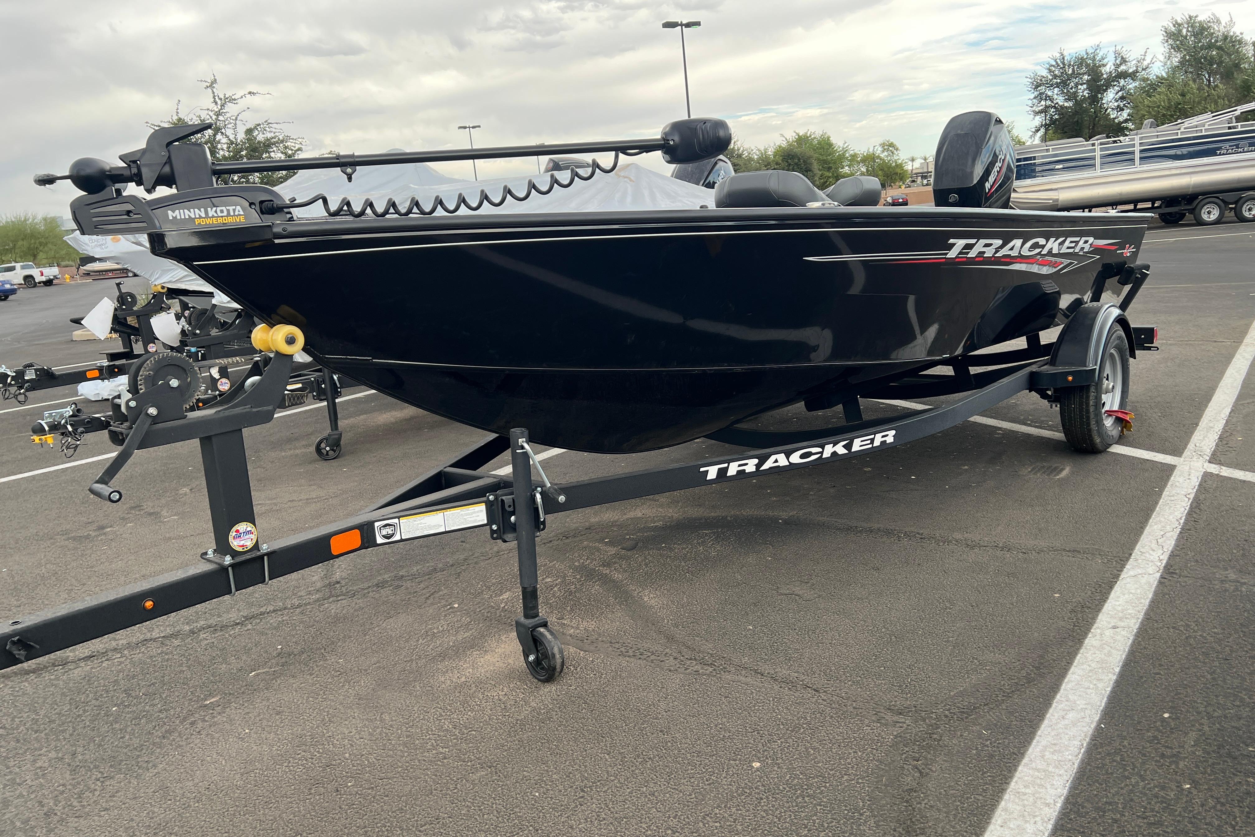 2025 Tracker Super Guide V-16 T boat on trailer in parking lot.