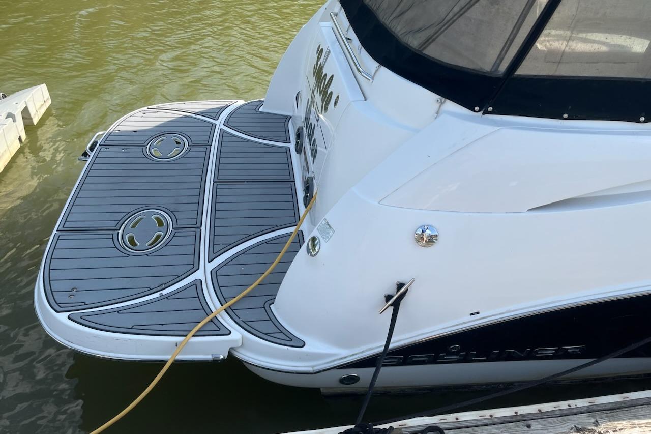 2012 Bayliner 285 Cruiser boat with sleek swim platform docked on calm water.