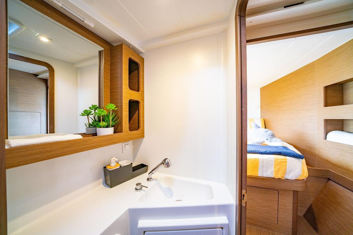 Luxurious interior of 2019 Lagoon 42 yacht featuring modern bathroom and cozy bedroom.