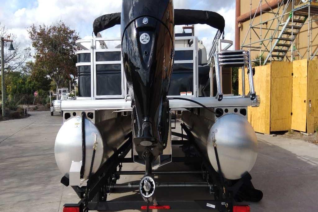 2026 Sun Tracker Fishin' Barge 22 DLX pontoon boat, rear view with motor and trailer.