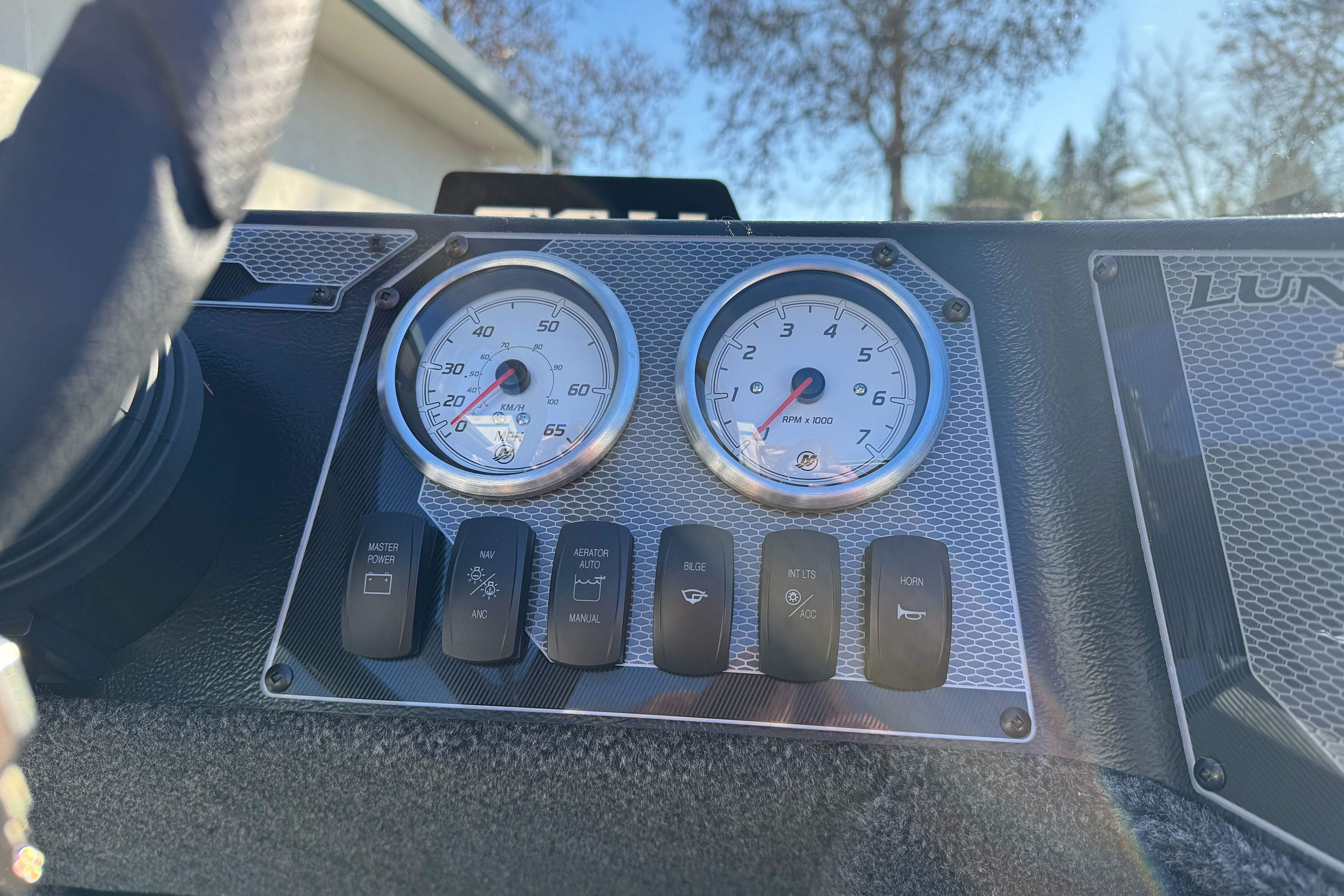 Dashboard of 2026 Lund 1650 Angler SS boat with gauges and control switches.