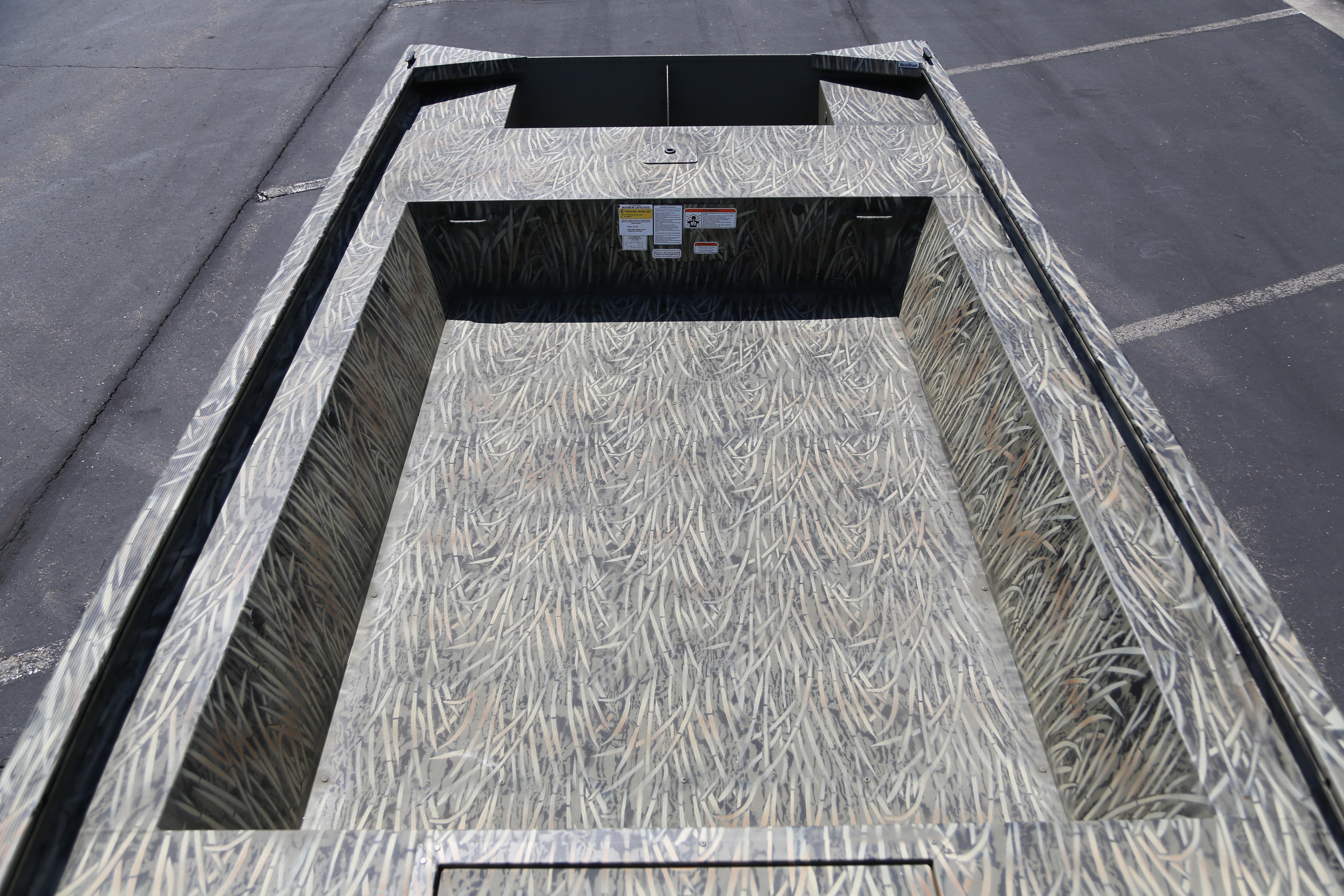 2026 Tracker Grizzly 1754 Utility boat with camouflage interior design on pavement.