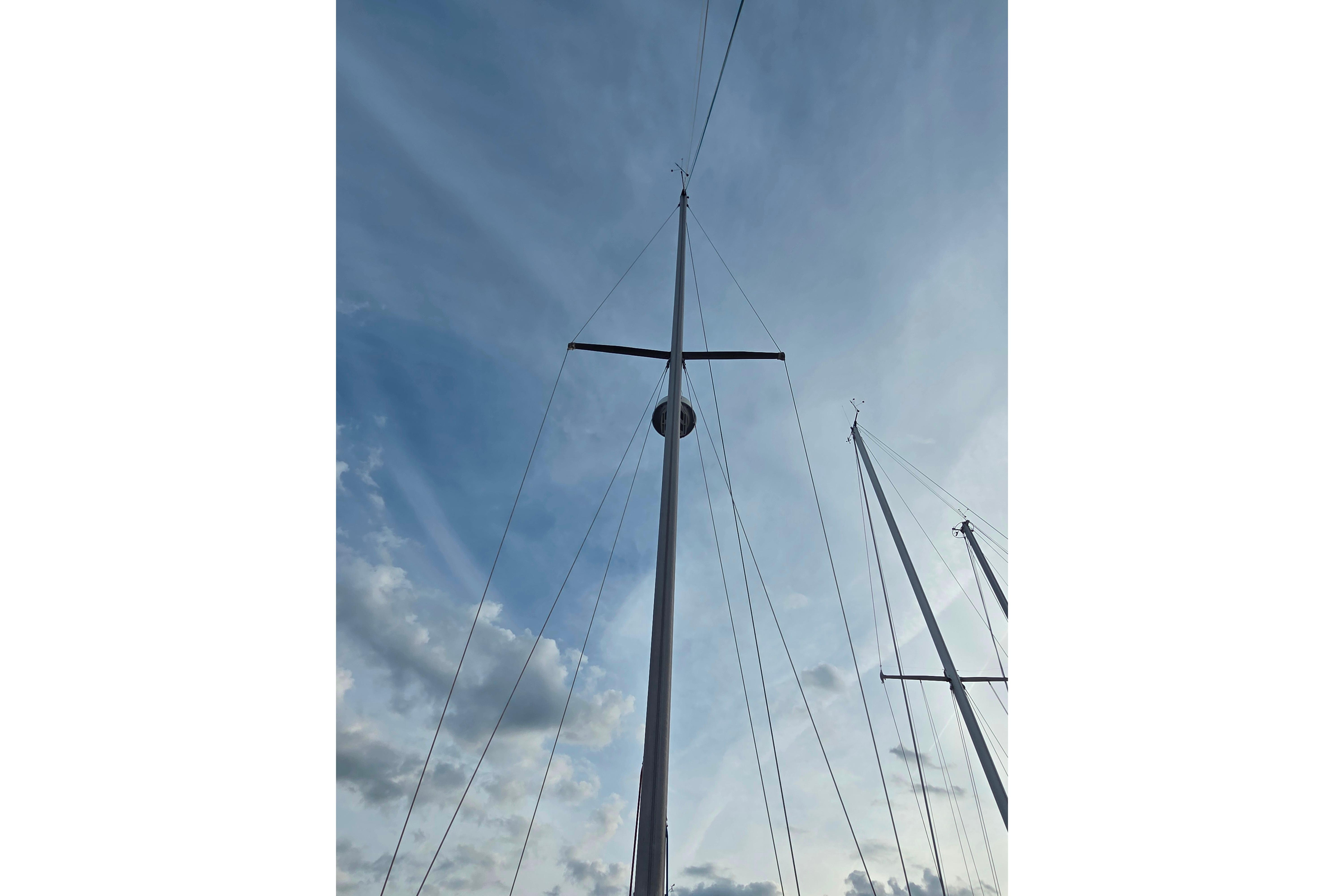 Tall mast of a 1986 Catalina 355 sailboat against a cloudy sky.