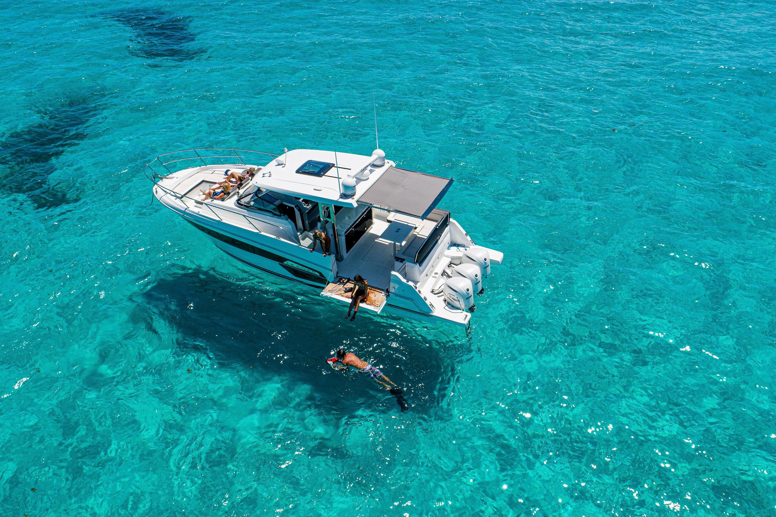 2026 Jeanneau Leader 12.5 WA yacht in clear turquoise waters, people swimming nearby.