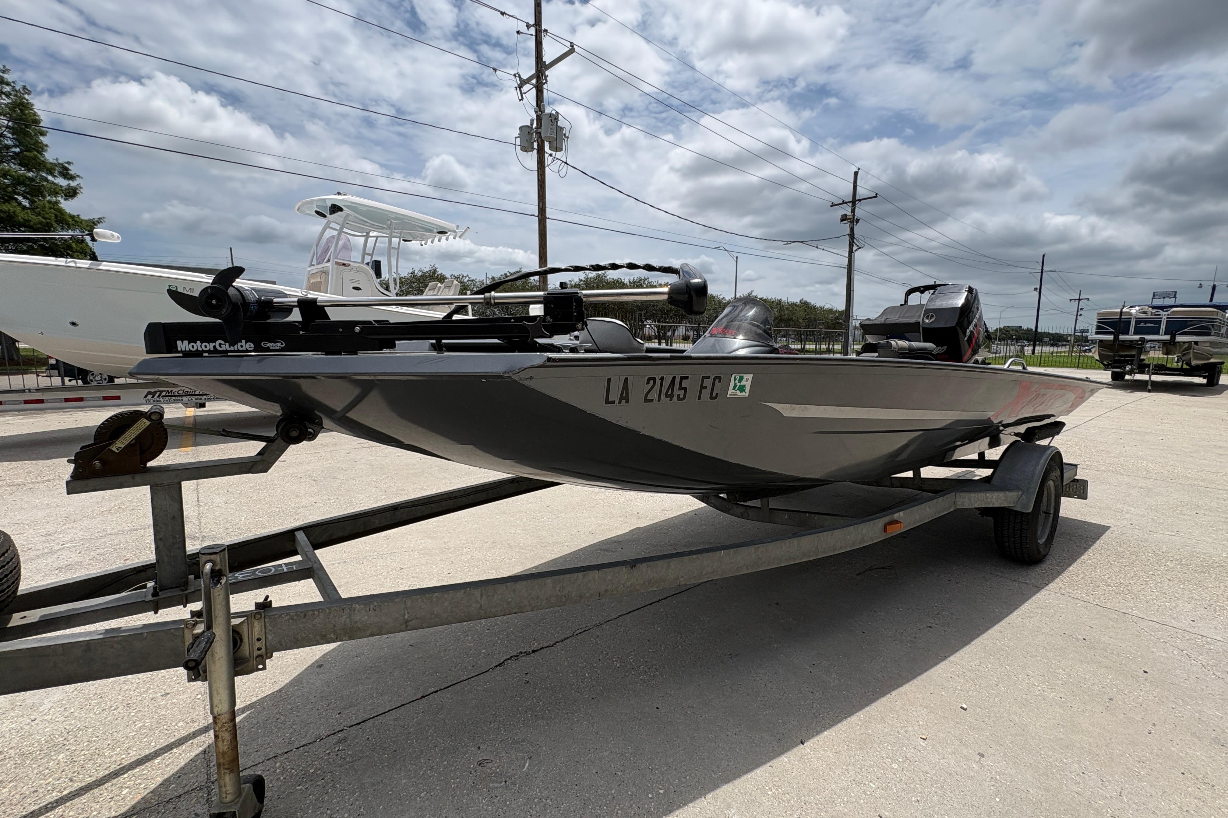 2000 Xpress X18 boat on trailer, parked outdoors under cloudy sky.