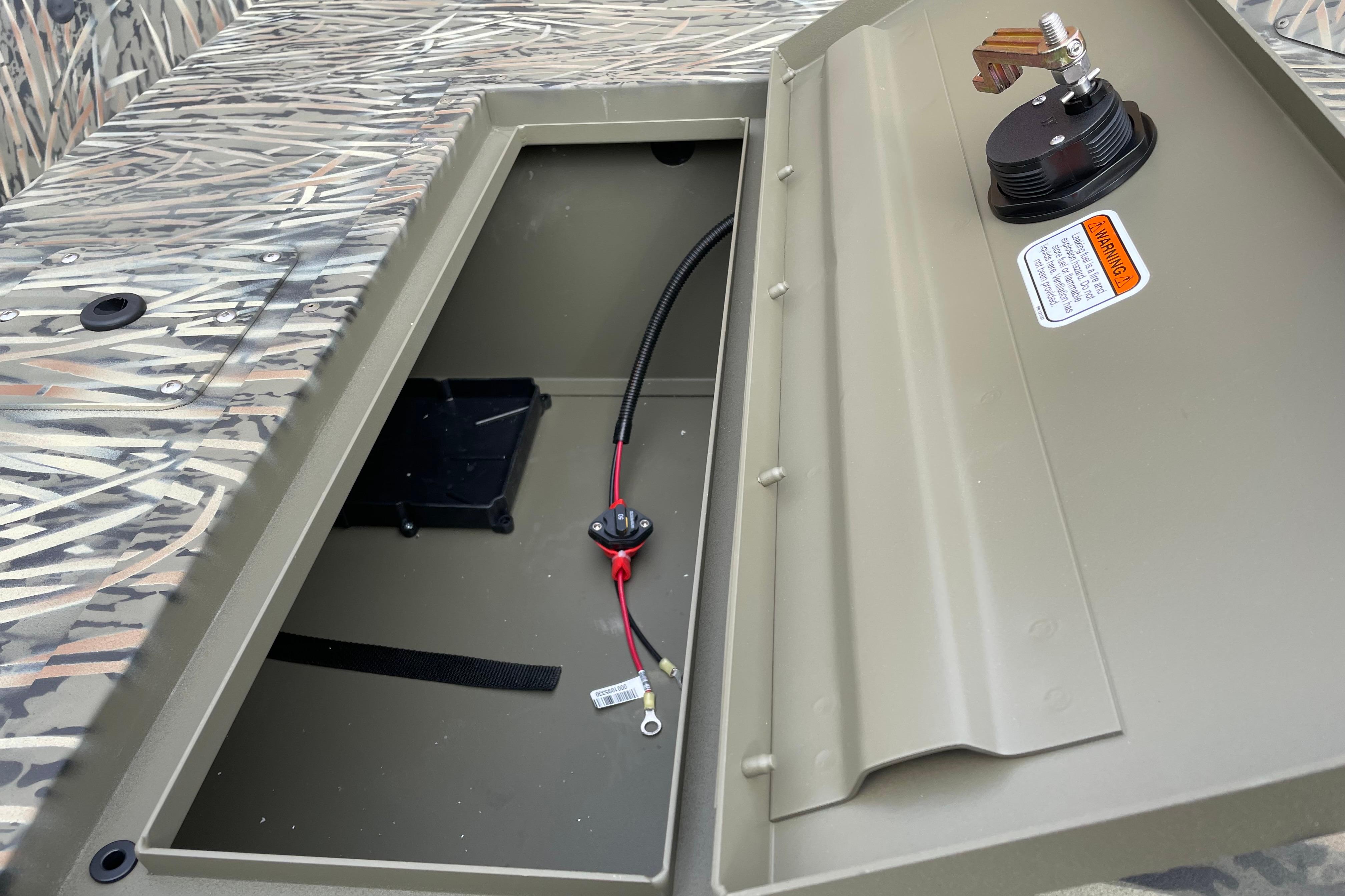 Open storage compartment of 2026 Tracker Grizzly 1648 SC boat with camouflage design.