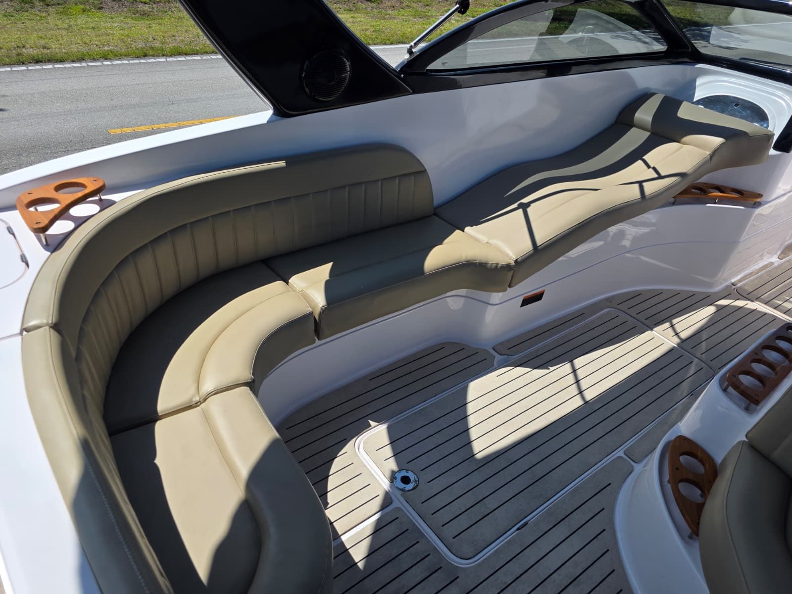 The image shows the cockpit of a Coral 26 boat with beige leather seating and wooden flooring.