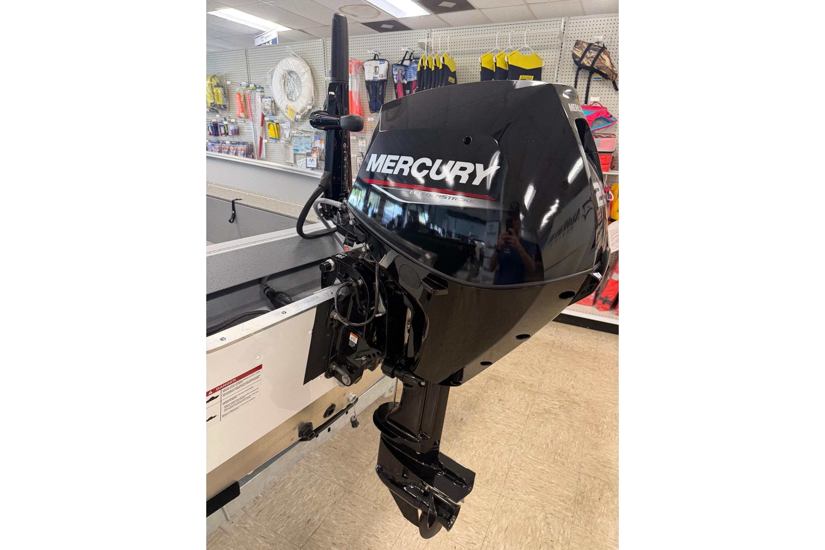 2026 Lund 1600 Fury Tiller with Mercury outboard motor in a showroom.