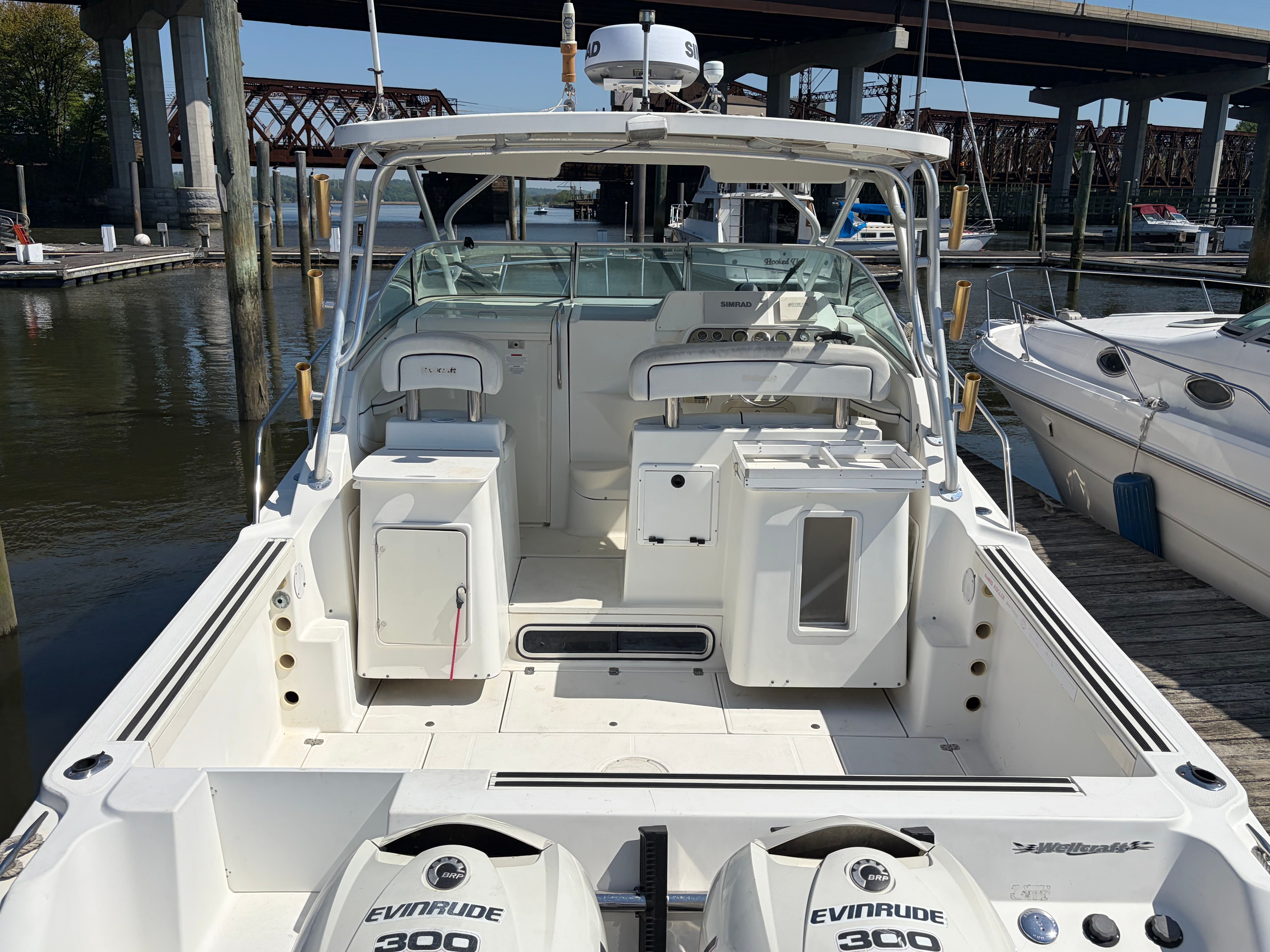The image shows a 2000 Wellcraft 290 Coastal boat docked, featuring two Evinrude engines.