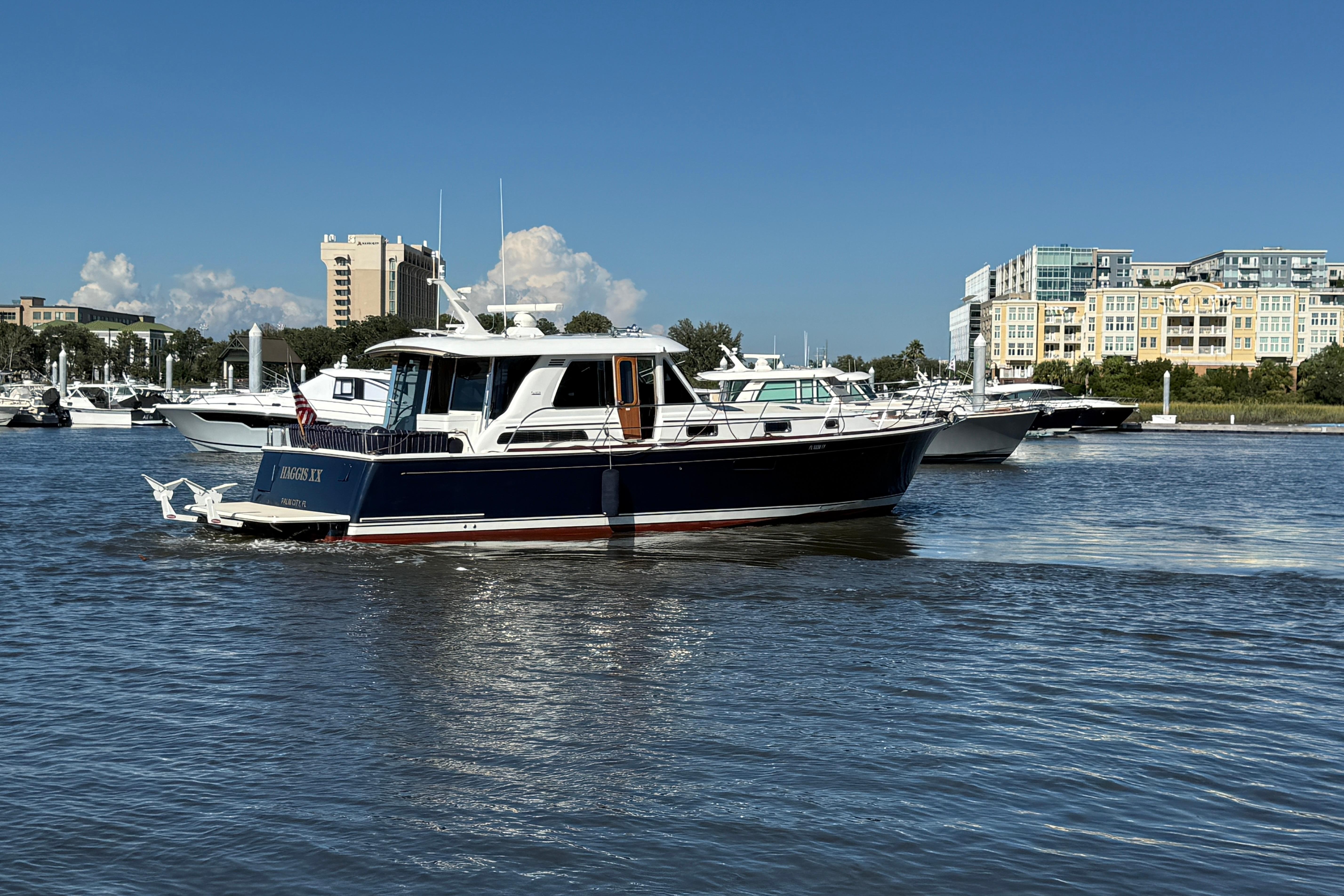 2017 Sabre 48 Salon Express yacht cruising in a marina with buildings in the background.