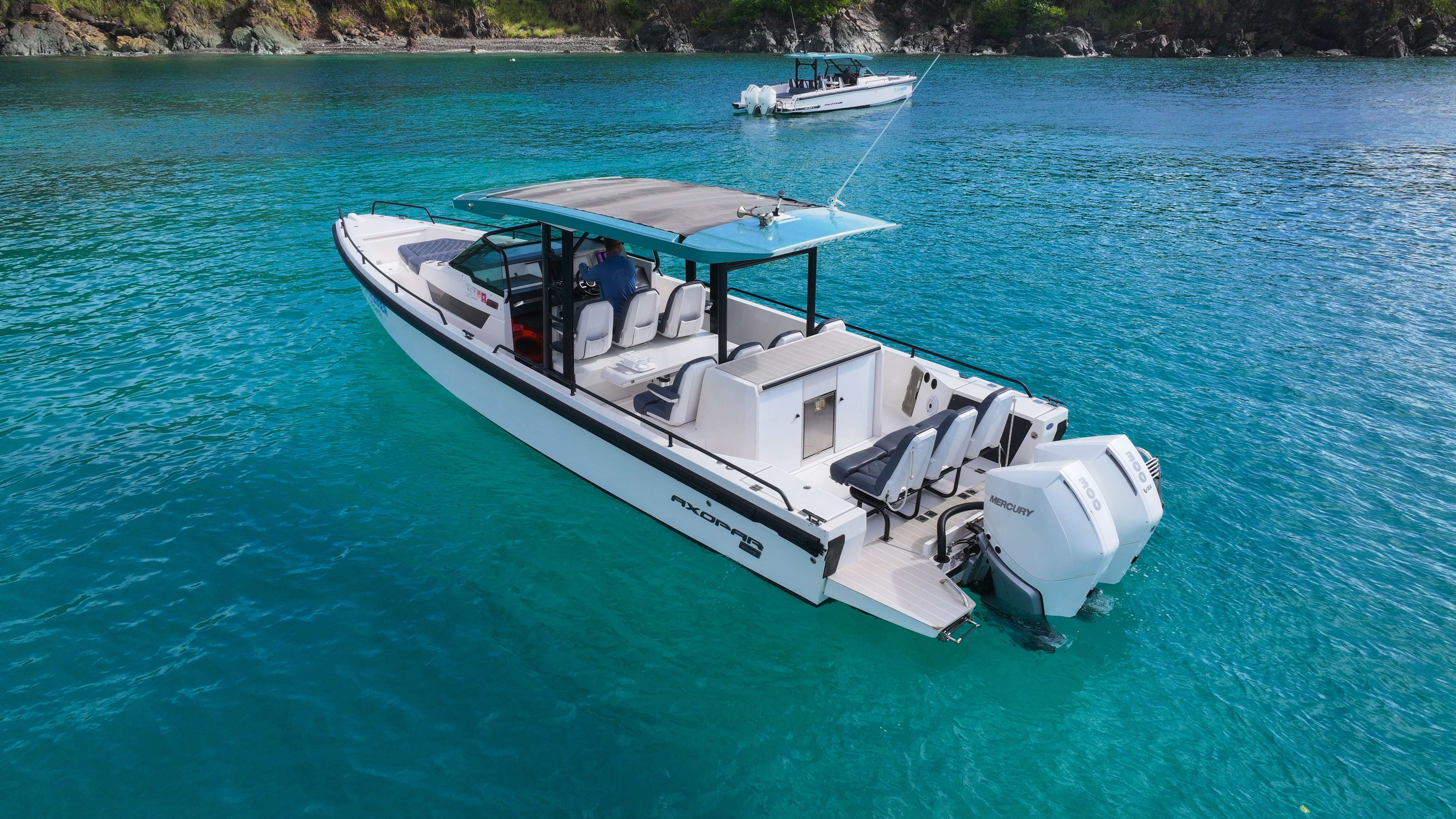A 2020 Axopar 37 SUN TOP on clear turquoise water with a rocky coastline in the background.
