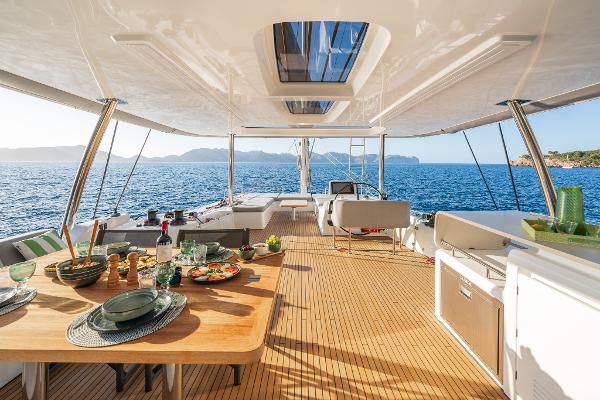 Luxurious Lagoon 60 yacht interior, 2025 model, with elegant dining setup and ocean view.